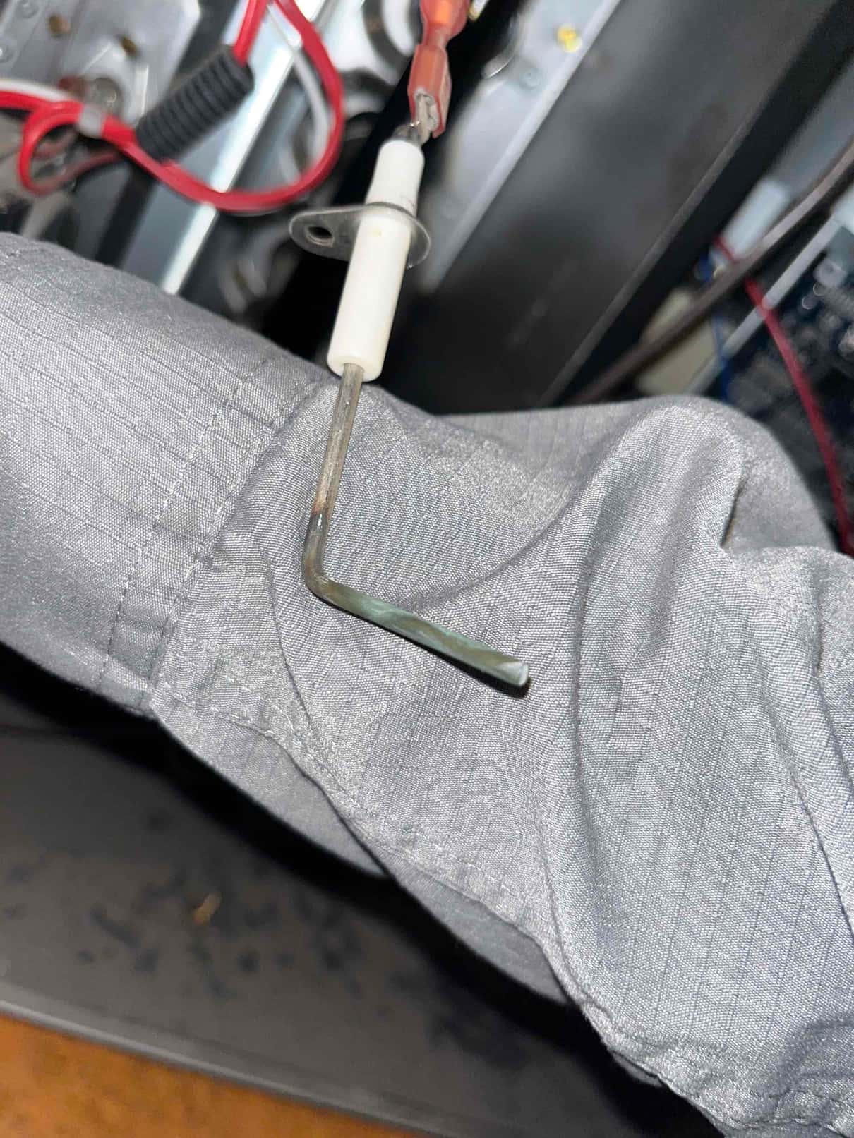 Flame sensor removed from a gas furnace, showing porcelain insulator, spade connector, and L-shaped rod.