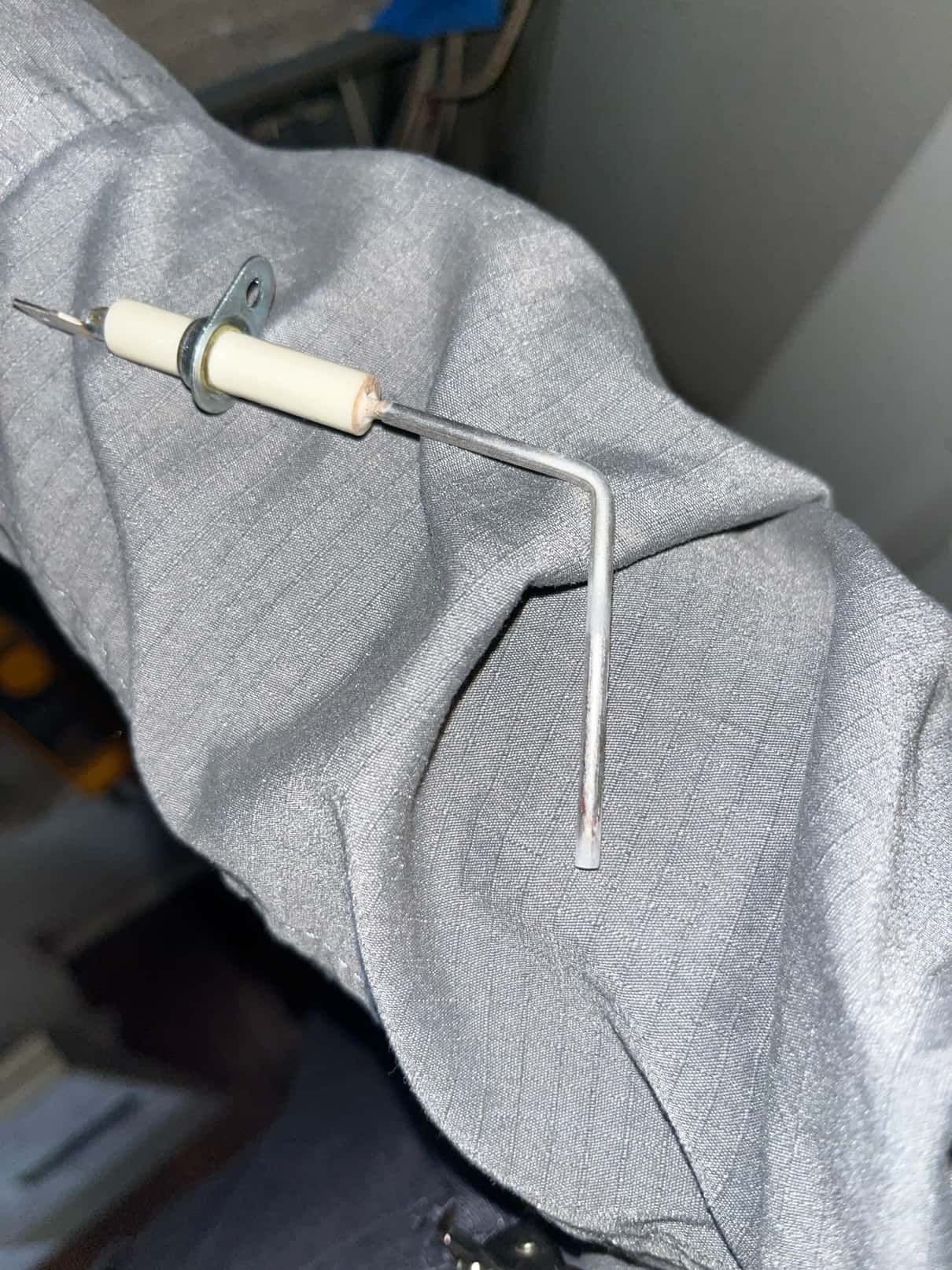 Flame sensor rod with ceramic insulator and mounting bracket resting on a work sleeve.