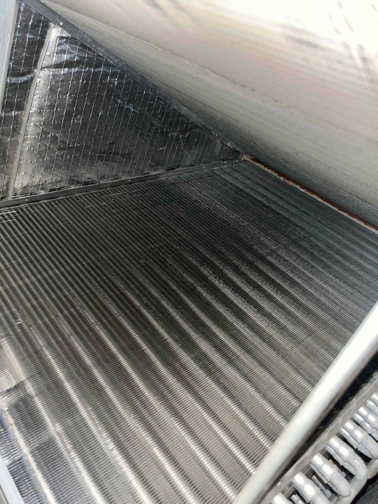 A-frame evaporator coil with clean aluminum fins and drain pan area visible inside air handler.