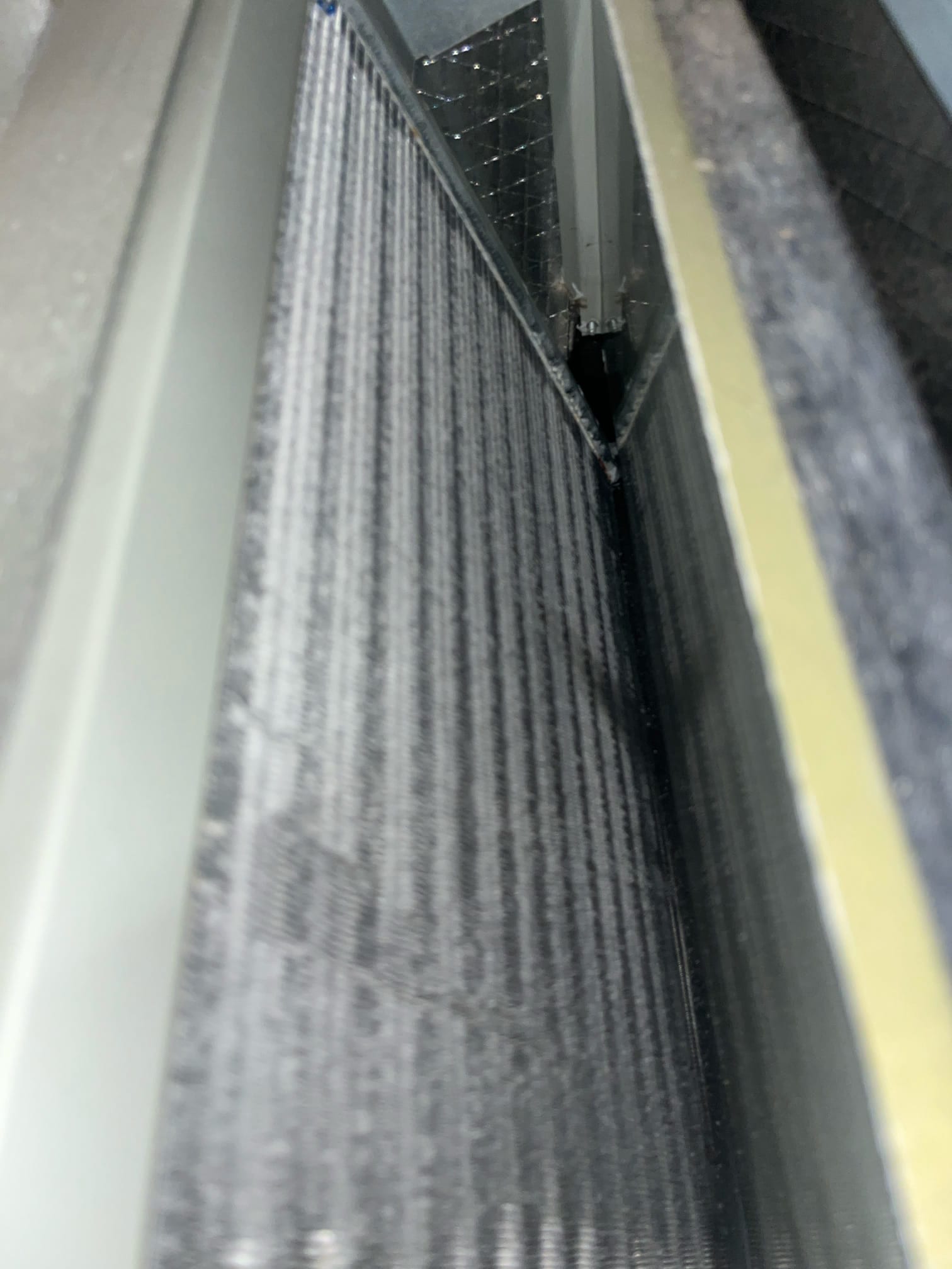 A-frame evaporator coil inside the air handler, showing clean aluminum fins and surrounding sheet-metal plenum.