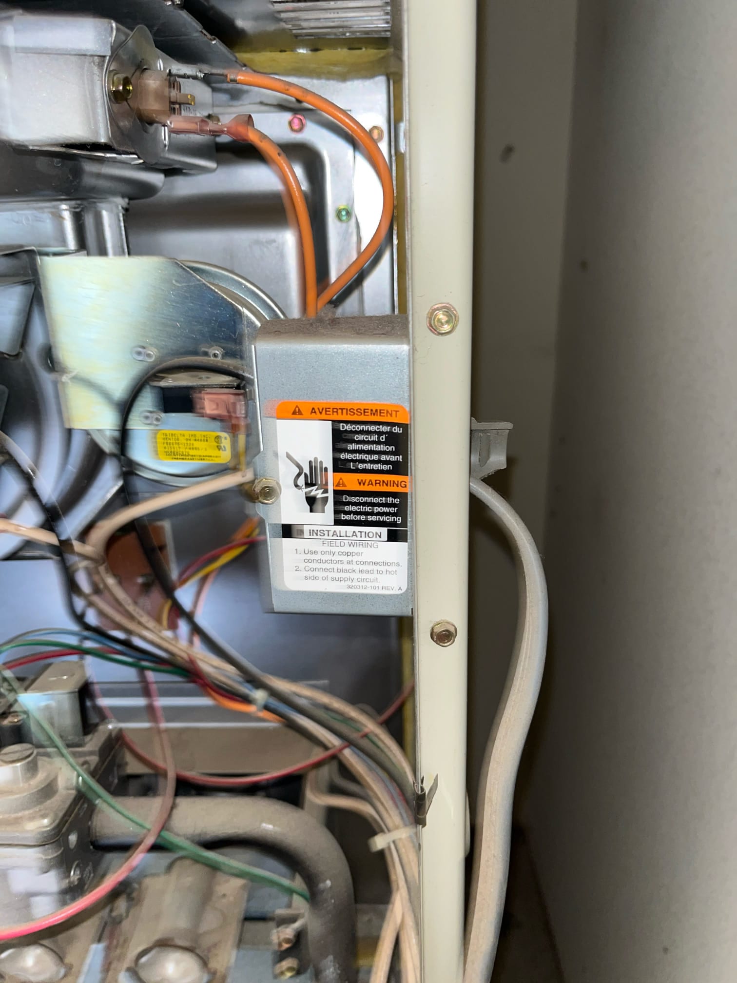 Furnace control compartment with wiring, gas valve, ignition components, and an electrical junction box with warning label.