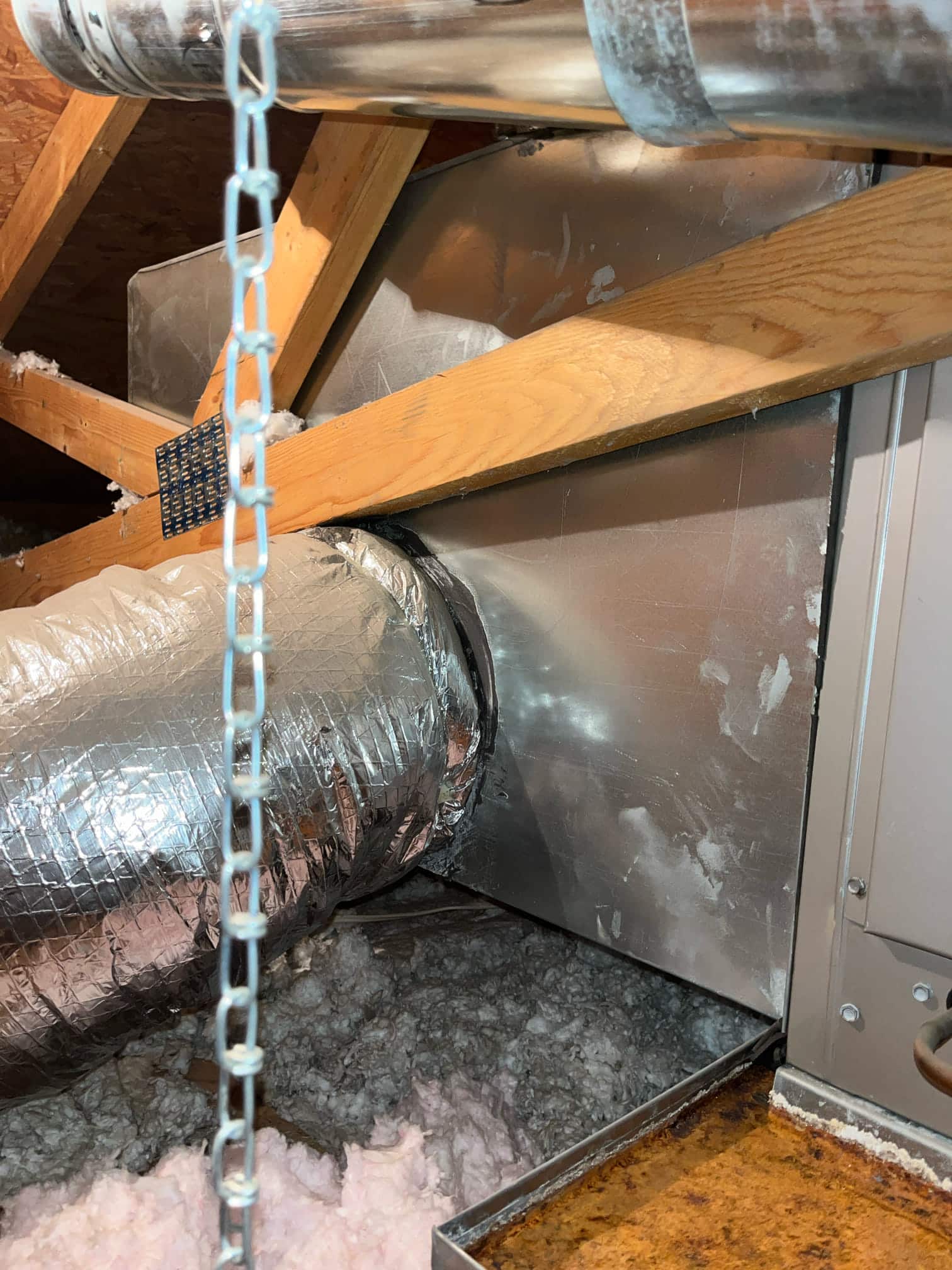 Insulated flex duct connected to a metal plenum at an attic air handler above a drain pan.