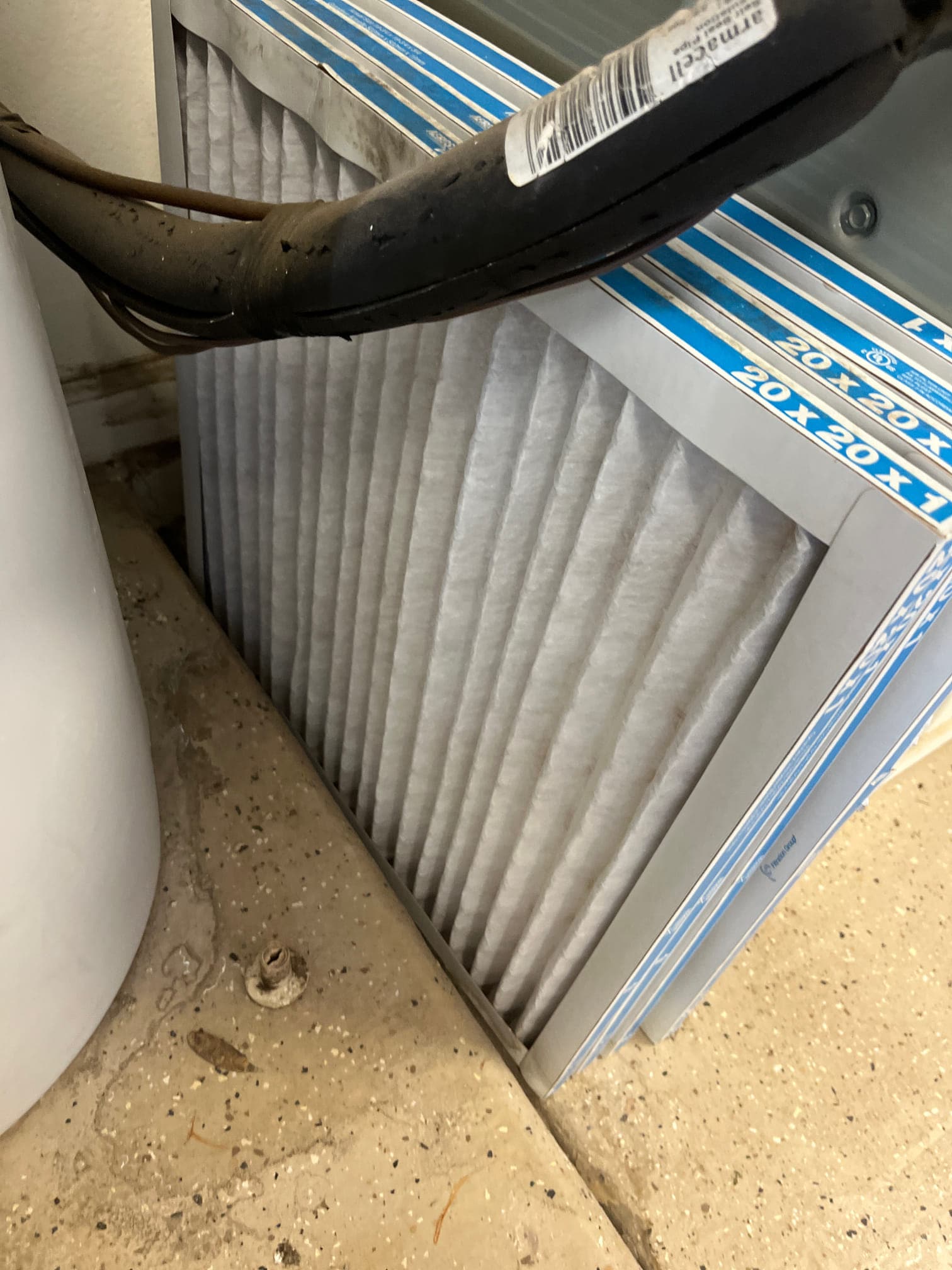 Pleated HVAC air filter labeled 20x20x1 sits beside an insulated refrigerant line near the indoor unit.