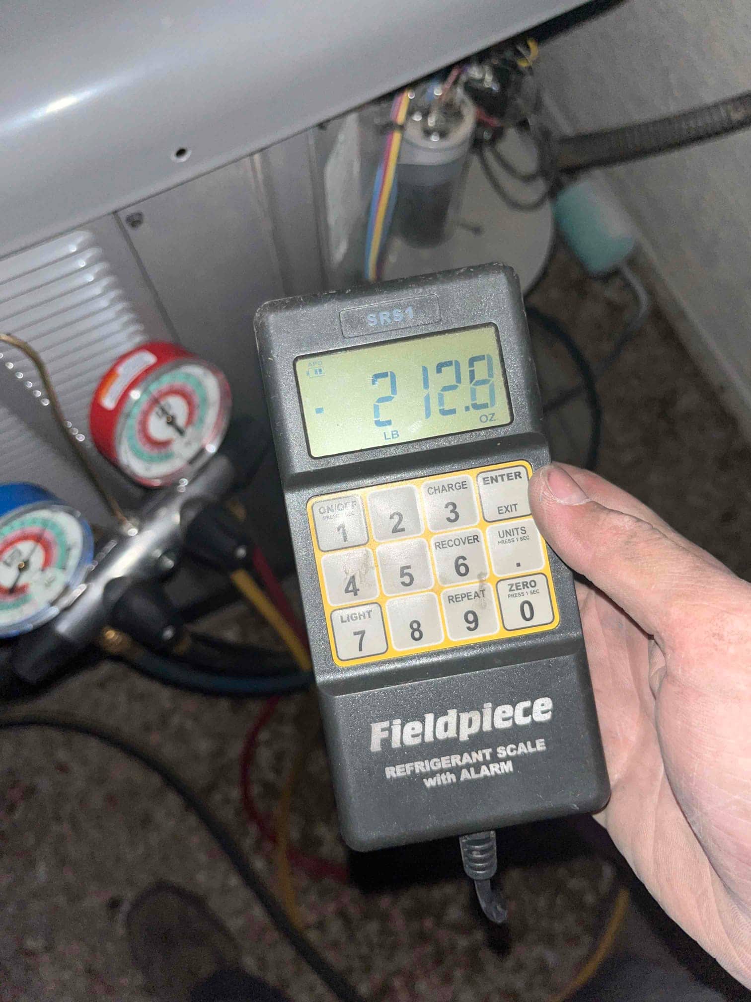 Refrigerant scale photographed during the service visit; no numerical reading is transcribed.