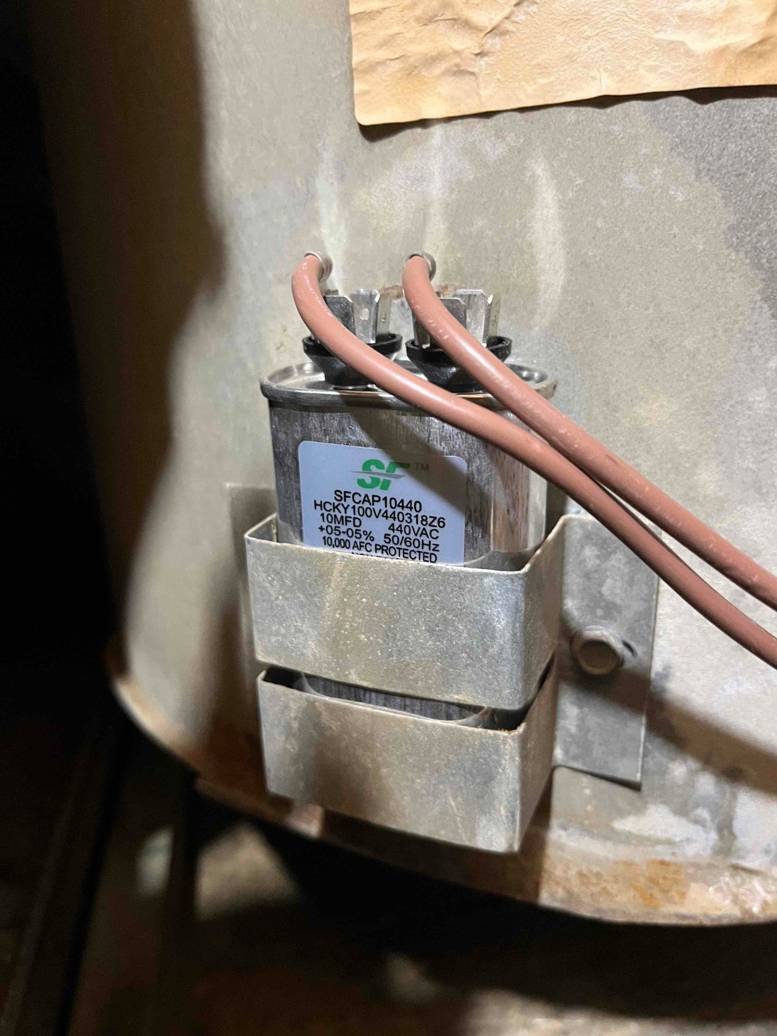 Run capacitor strapped to a motor housing with two brown wires connected, labeled 10 µF 440VAC.