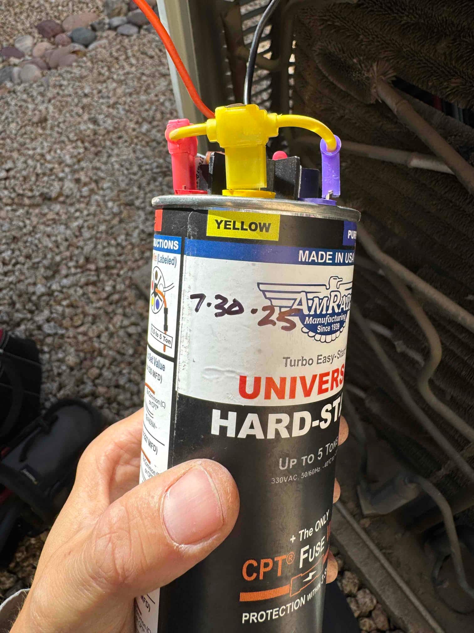 Universal hard-start kit labeled 'UP TO 5 TON, 330VAC' with red, yellow, and purple connectors near condenser coil.