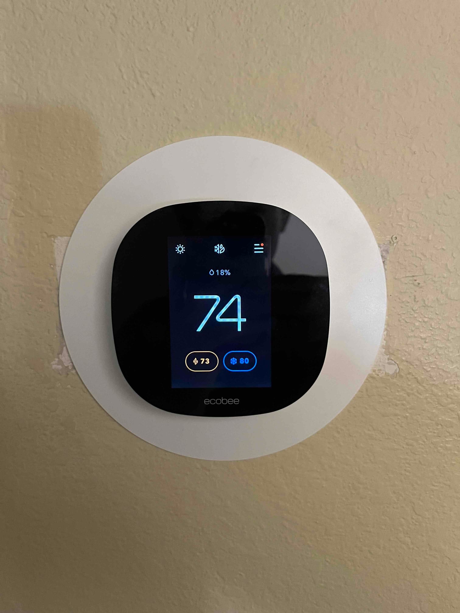 Wall-mounted smart thermostat displays 74 degrees with heating set to 73 and cooling set to 80.