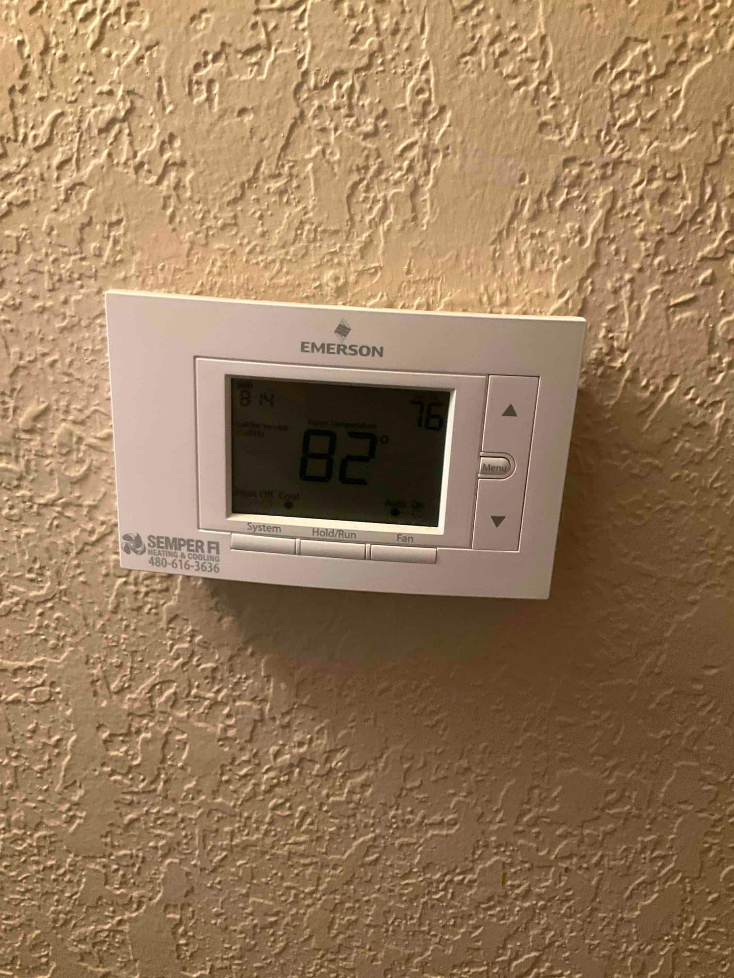 Wall-mounted thermostat displaying room temperature 82° and setpoint 76°, with system and fan buttons visible.