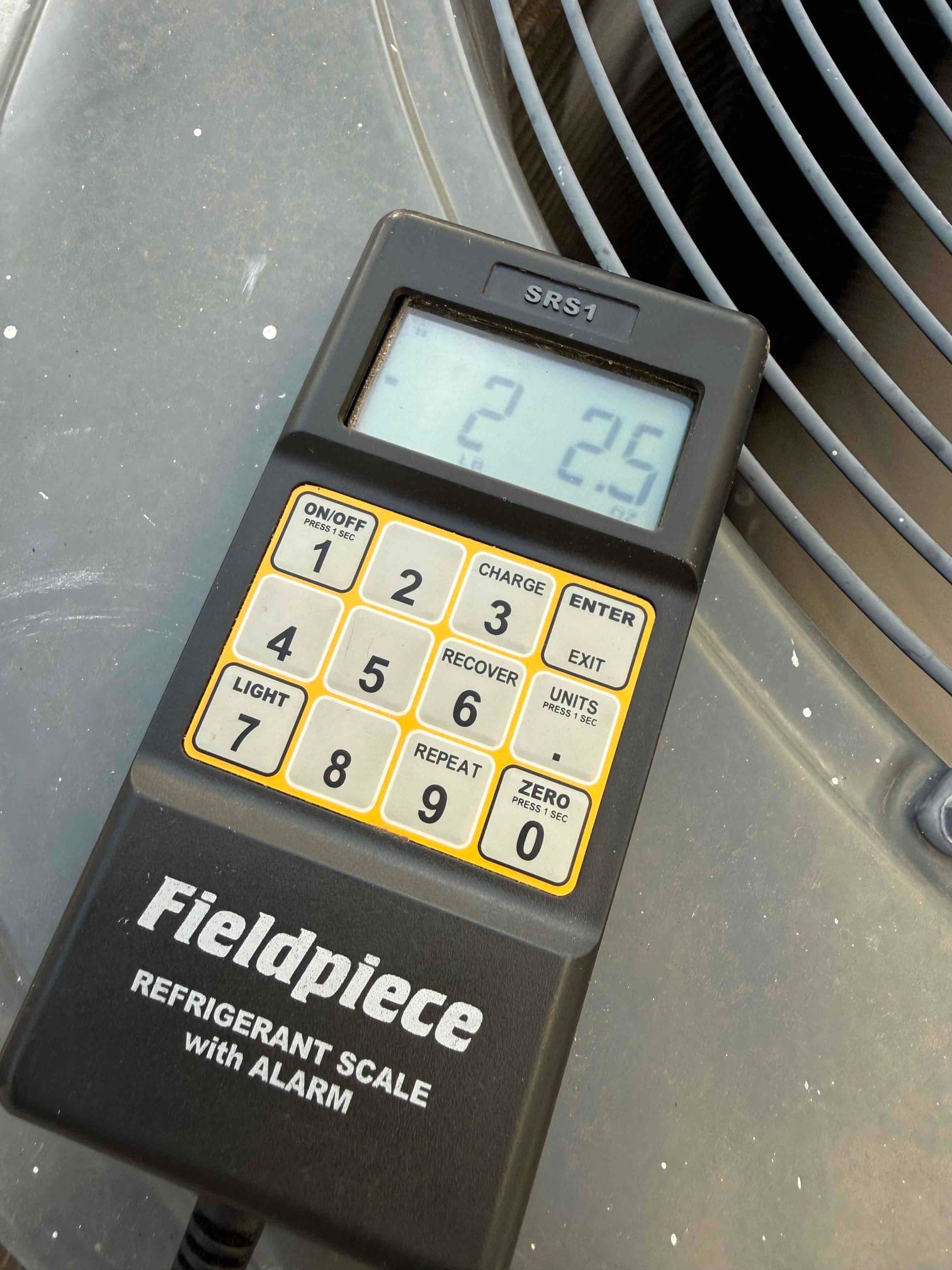 Refrigerant scale photographed during the service visit; no numerical reading is transcribed.