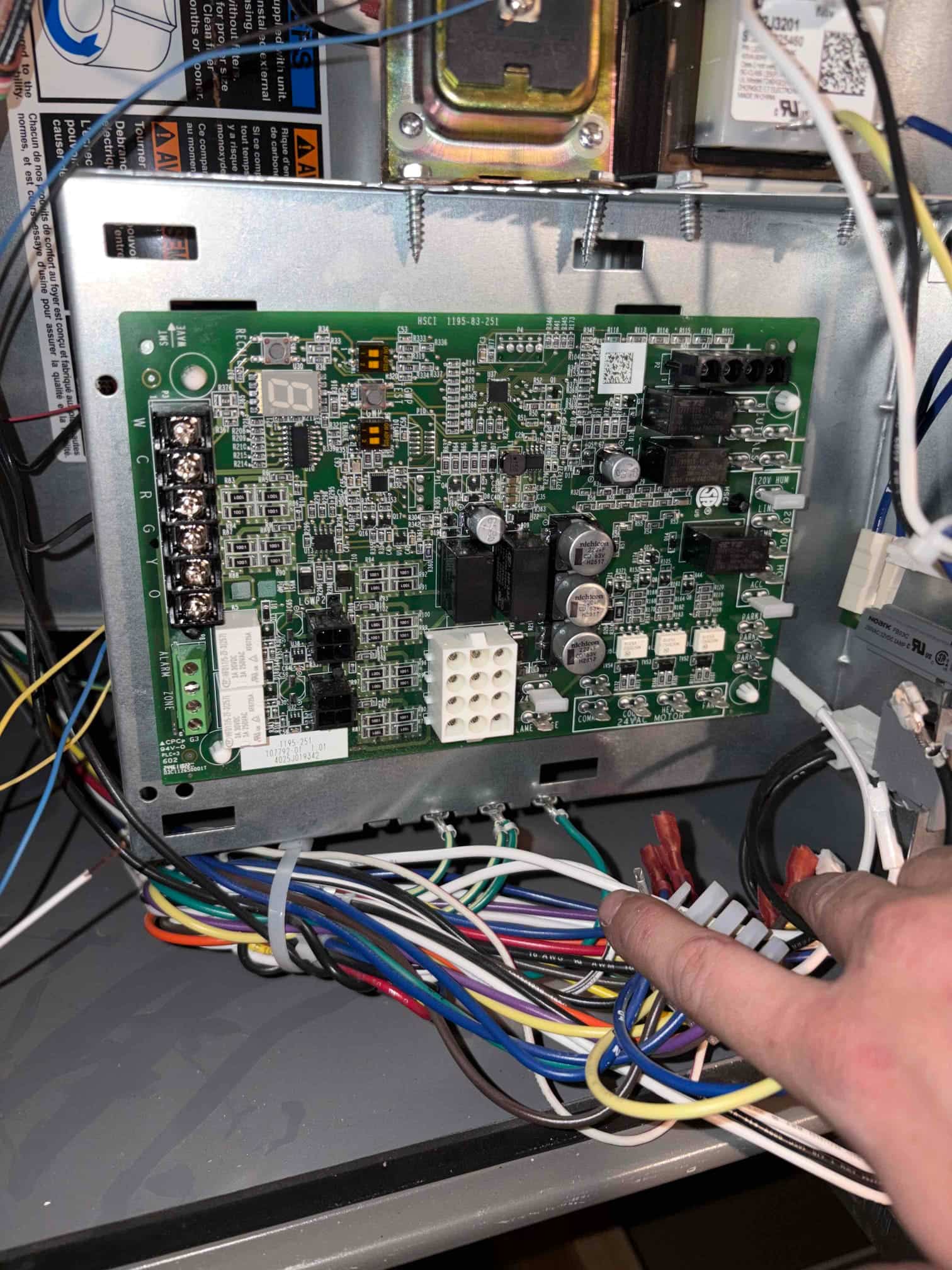 Furnace control board mounted in the cabinet with relays, fuses, and connected low- and high-voltage wiring harnesses.