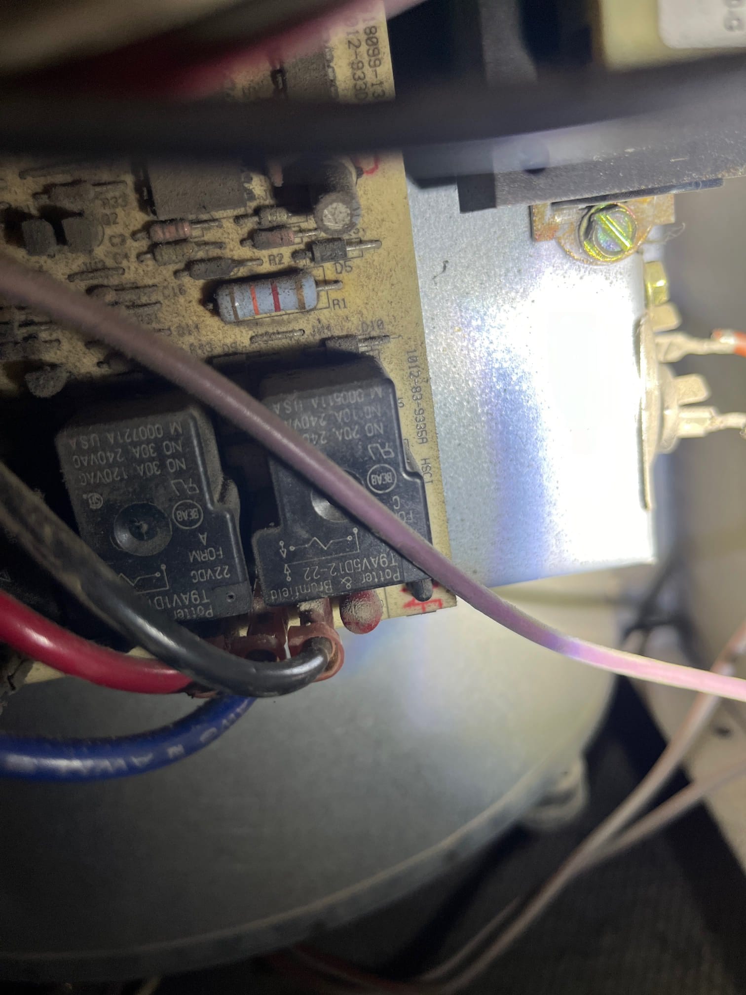 Close-up of an HVAC control board showing relays, a resistor, wiring connections, and accumulated dust.