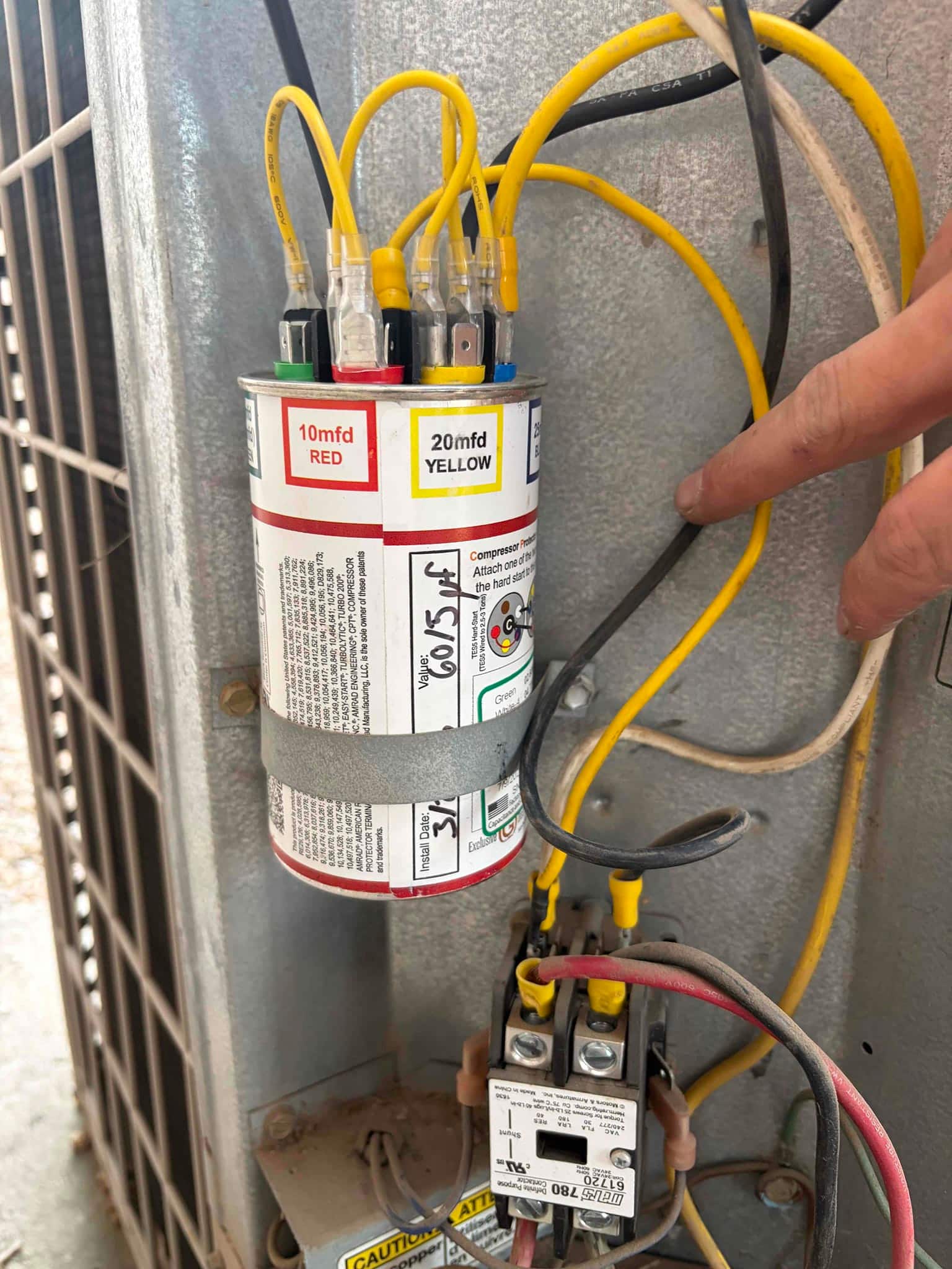 Color-coded multi-tap run capacitor labeled 10 mfd RED and 20 mfd YELLOW with wiring connected beside the contactor.