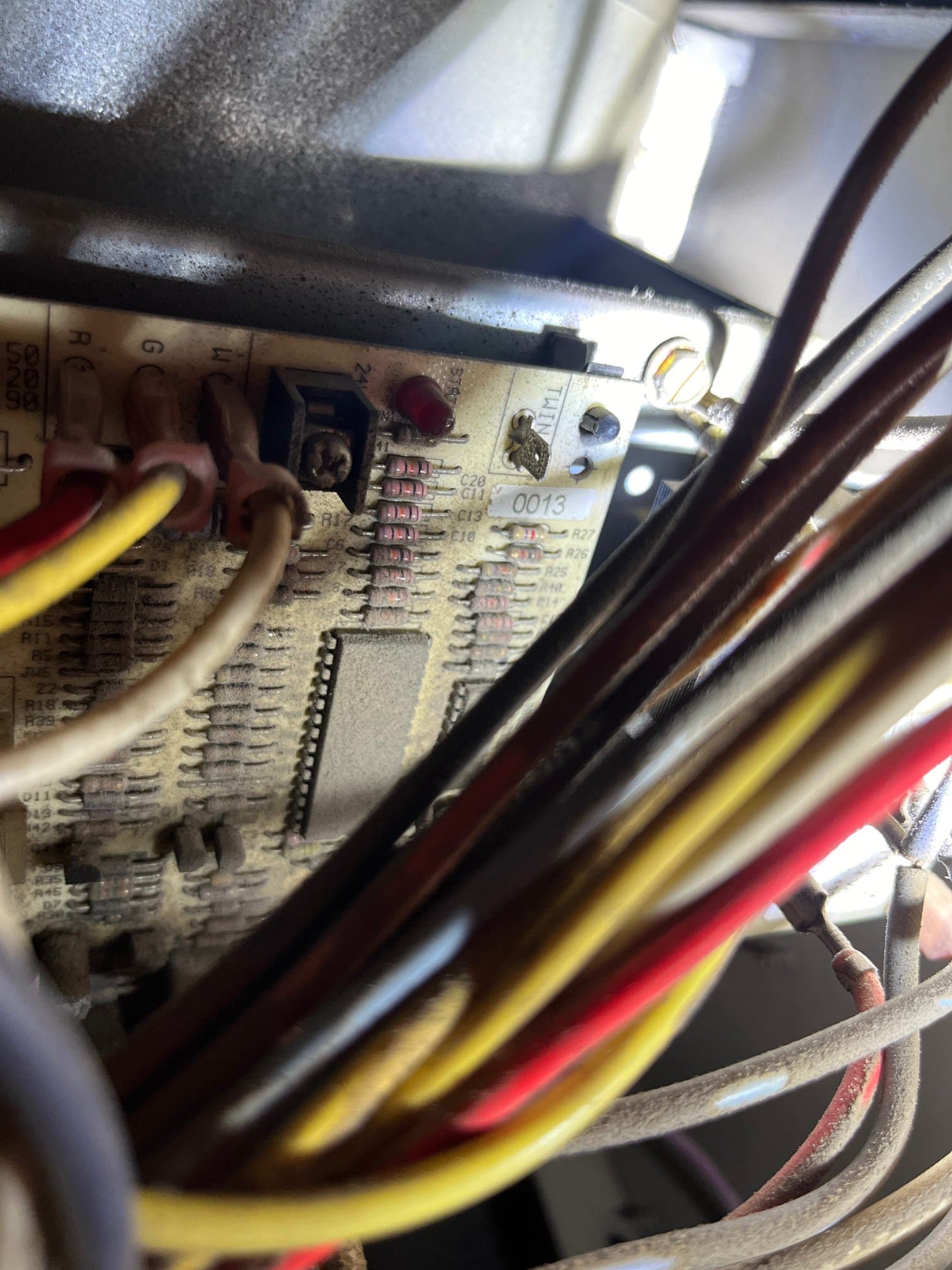 Furnace control board with R, G, W terminals and multiple colored wires connected, showing a red status LED.