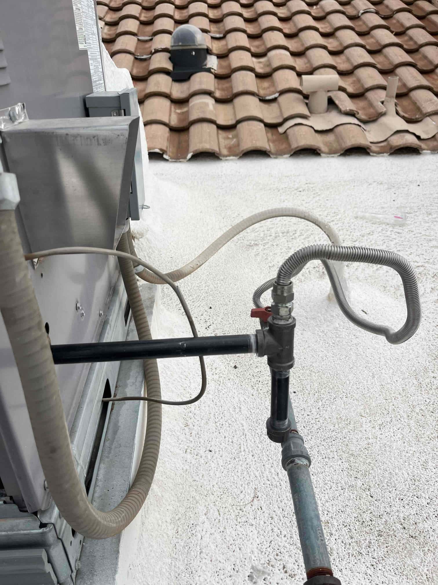 Gas supply piping with shutoff valve and flexible conduit next to rooftop package unit.