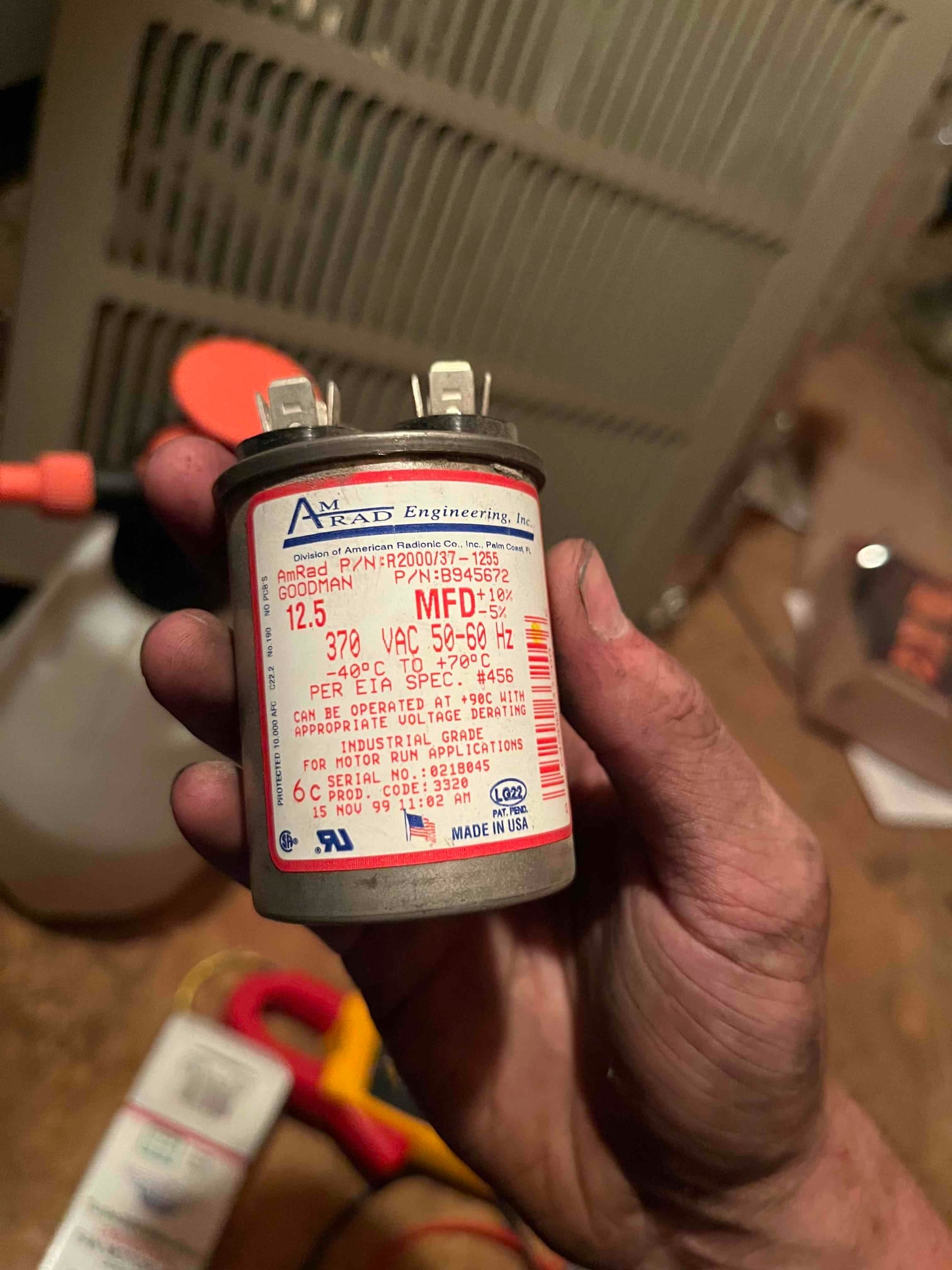 Motor run capacitor labeled 12.5 MFD, 370 VAC 50–60 Hz, showing two blade terminals, held near HVAC equipment.