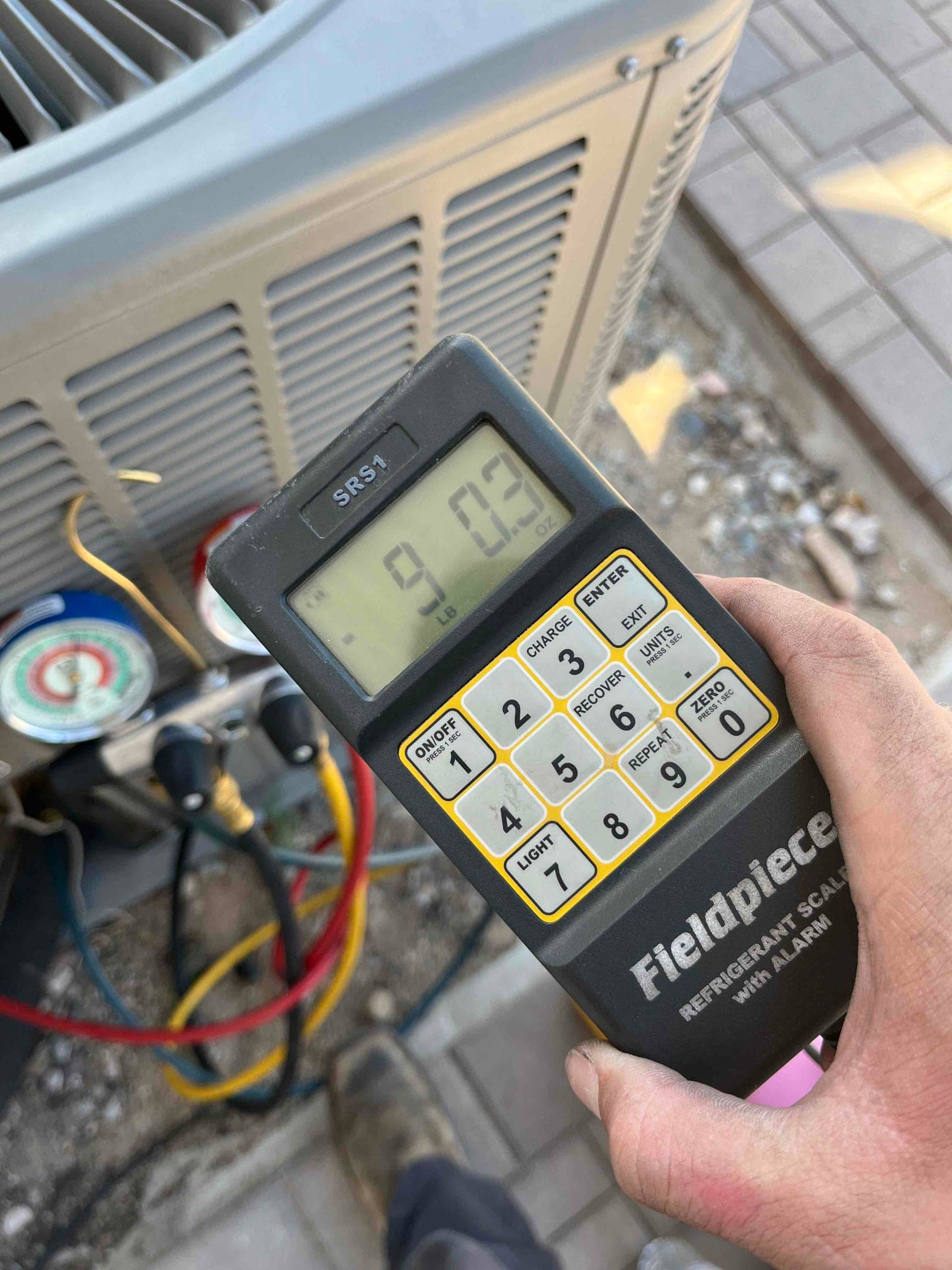 Refrigerant scale photographed during the service visit; no numerical reading is transcribed.