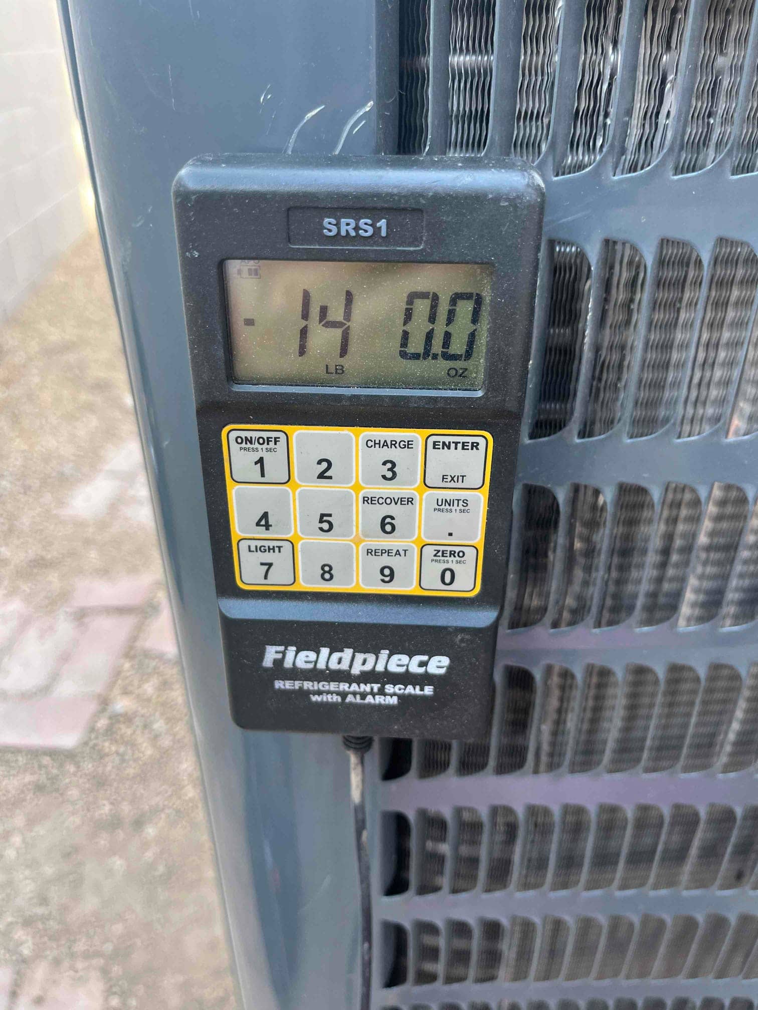 Refrigerant scale photographed during the service visit; no numerical reading is transcribed.