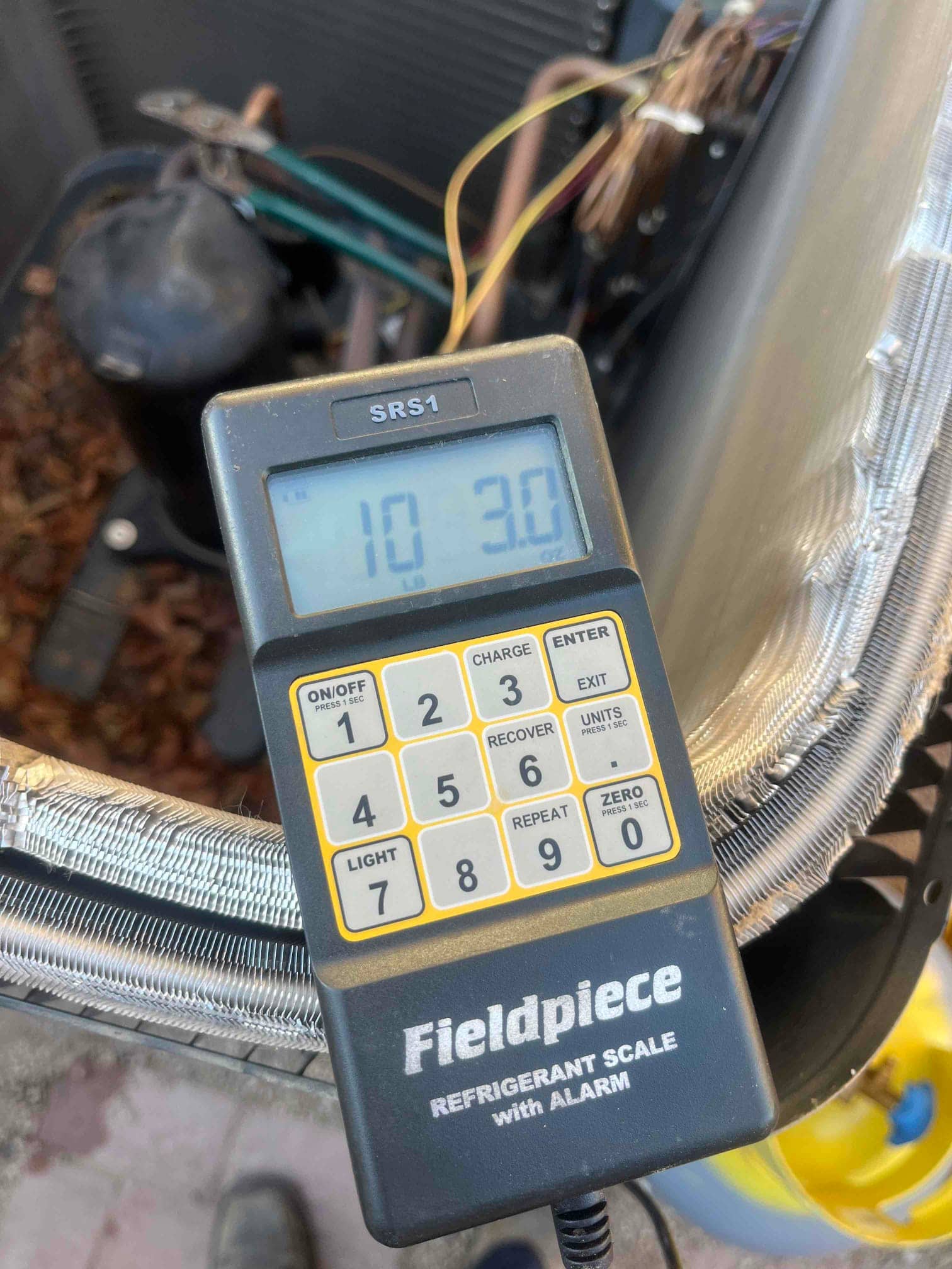 Refrigerant scale photographed during the service visit; no numerical reading is transcribed.