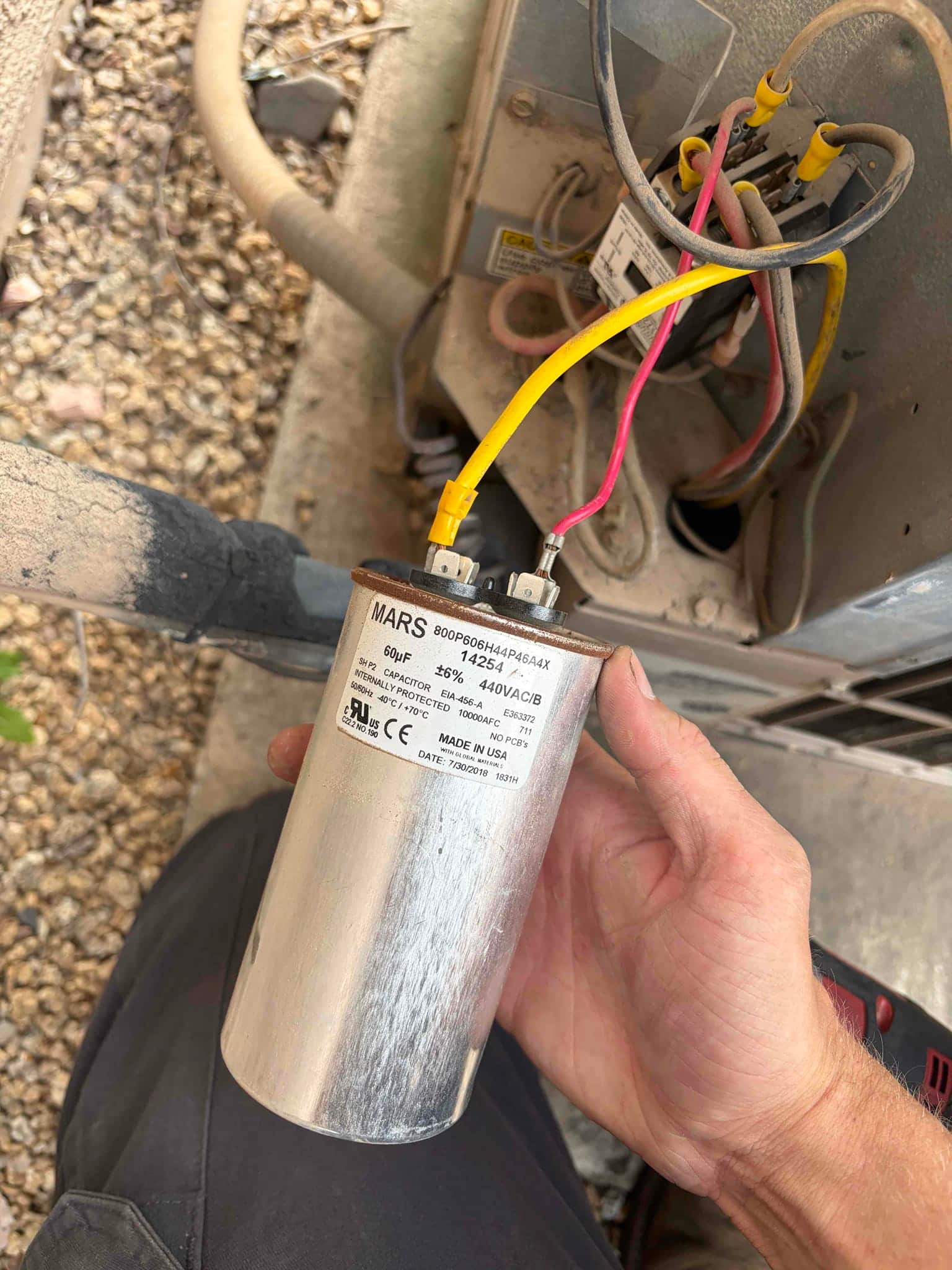 Run capacitor held near condenser wiring, labeled 60 μF ±6% 440VAC, with yellow and pink leads connected to its terminals.
