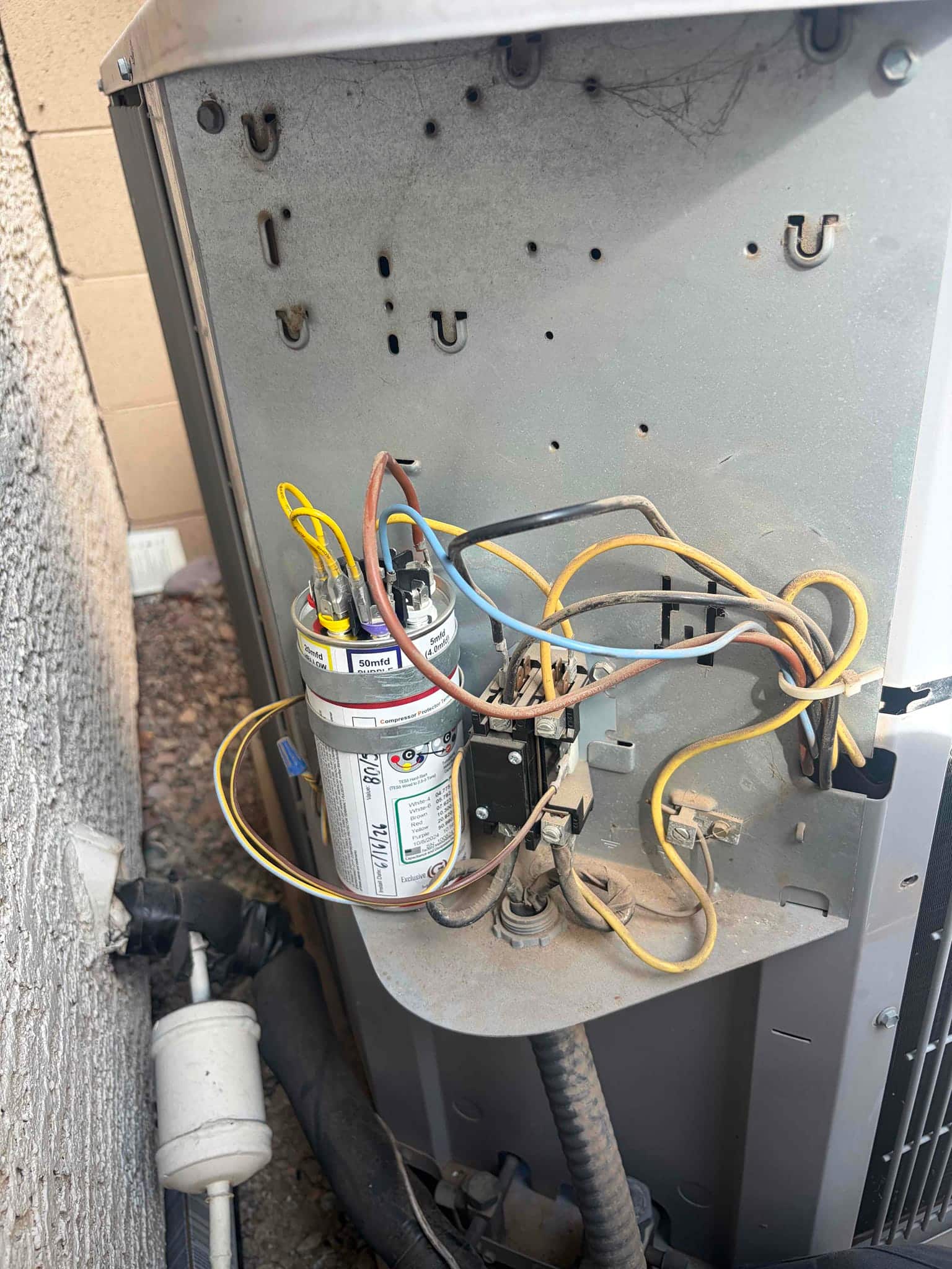 Run capacitor labeled 50 mfd with multiple wires connected, mounted next to contactor inside the outdoor condenser cabinet.