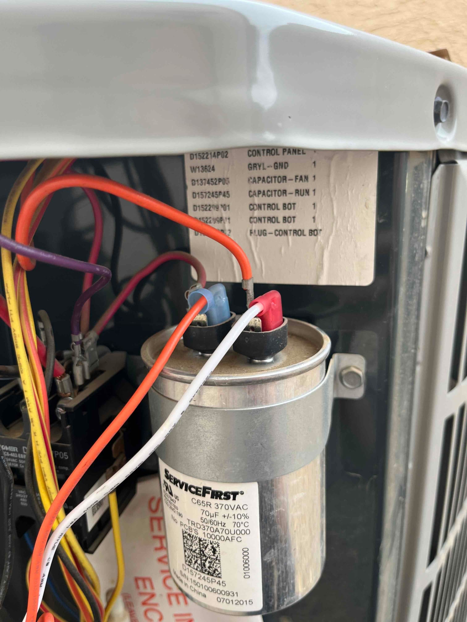 Run capacitor mounted in the condenser compartment with wiring connected; label shows 70 μF, 370 VAC rating.