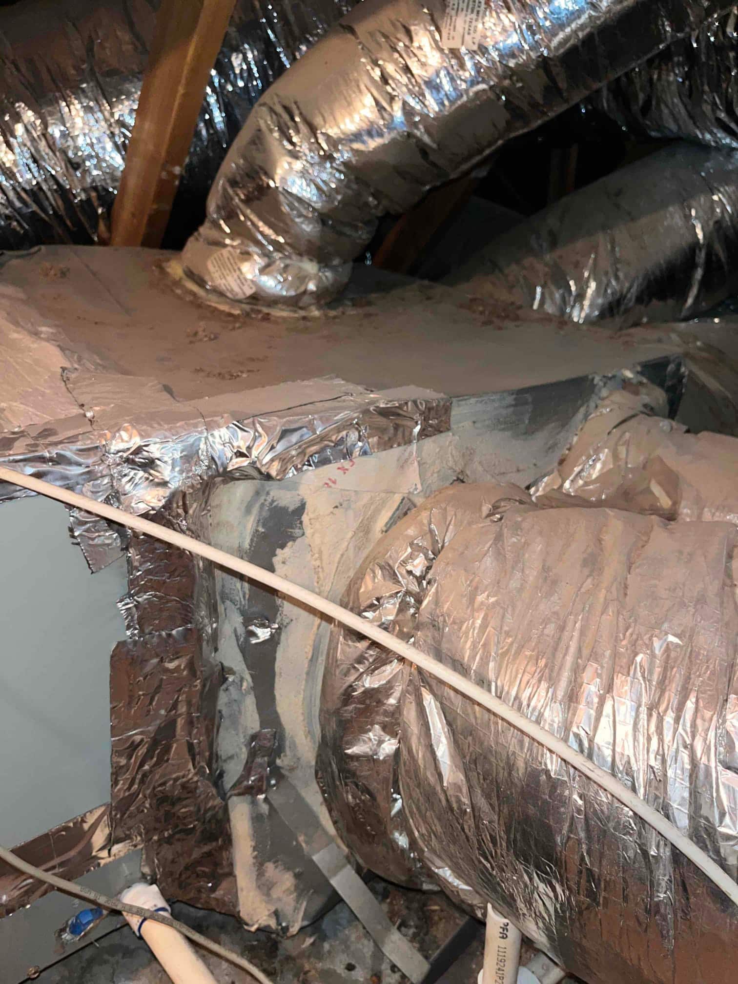 Sheet-metal supply plenum with multiple insulated flex ducts attached using foil tape and mastic.