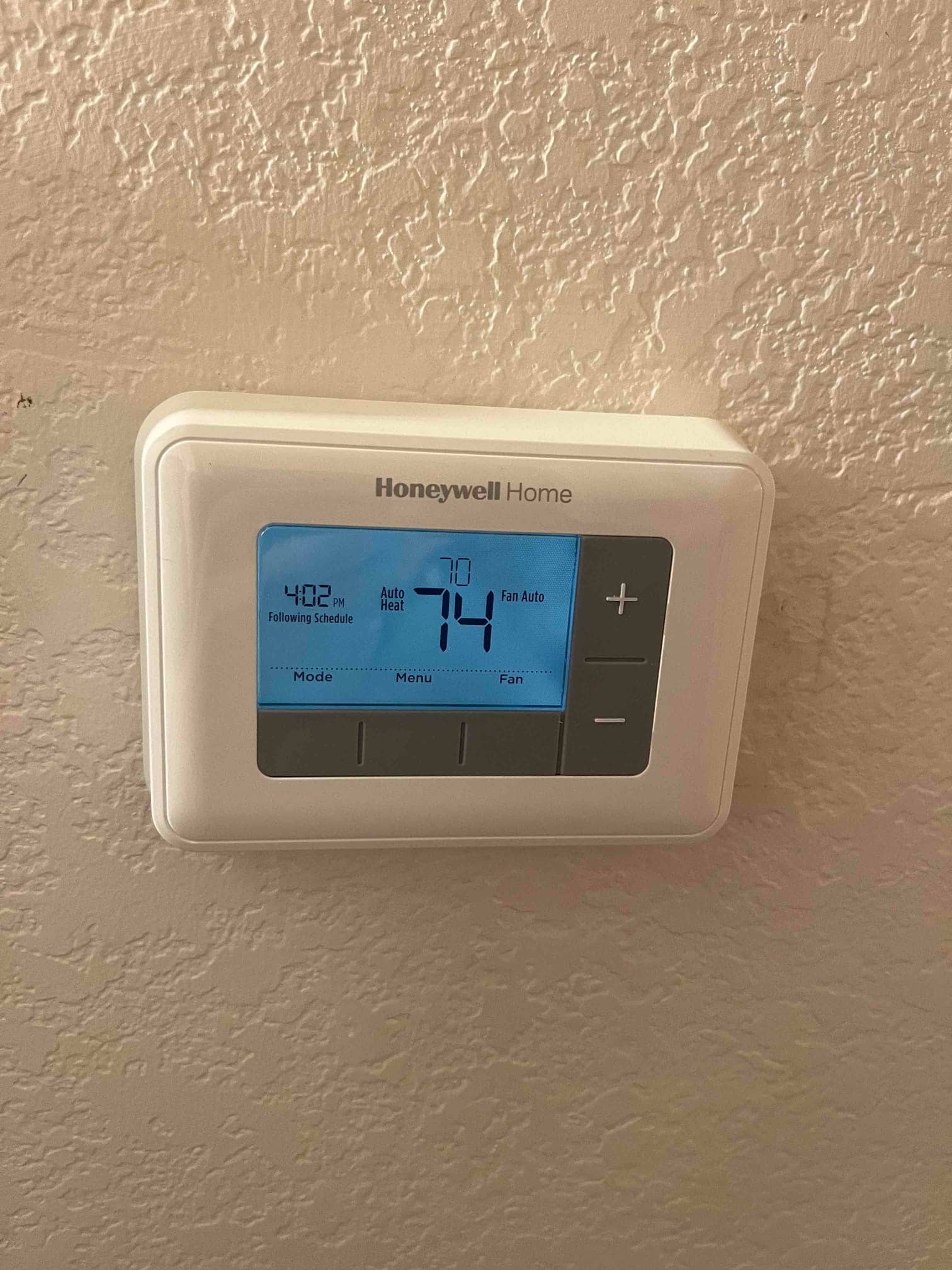 Wall-mounted digital thermostat shows 74°F room temperature, set to heat mode with fan set to Auto.