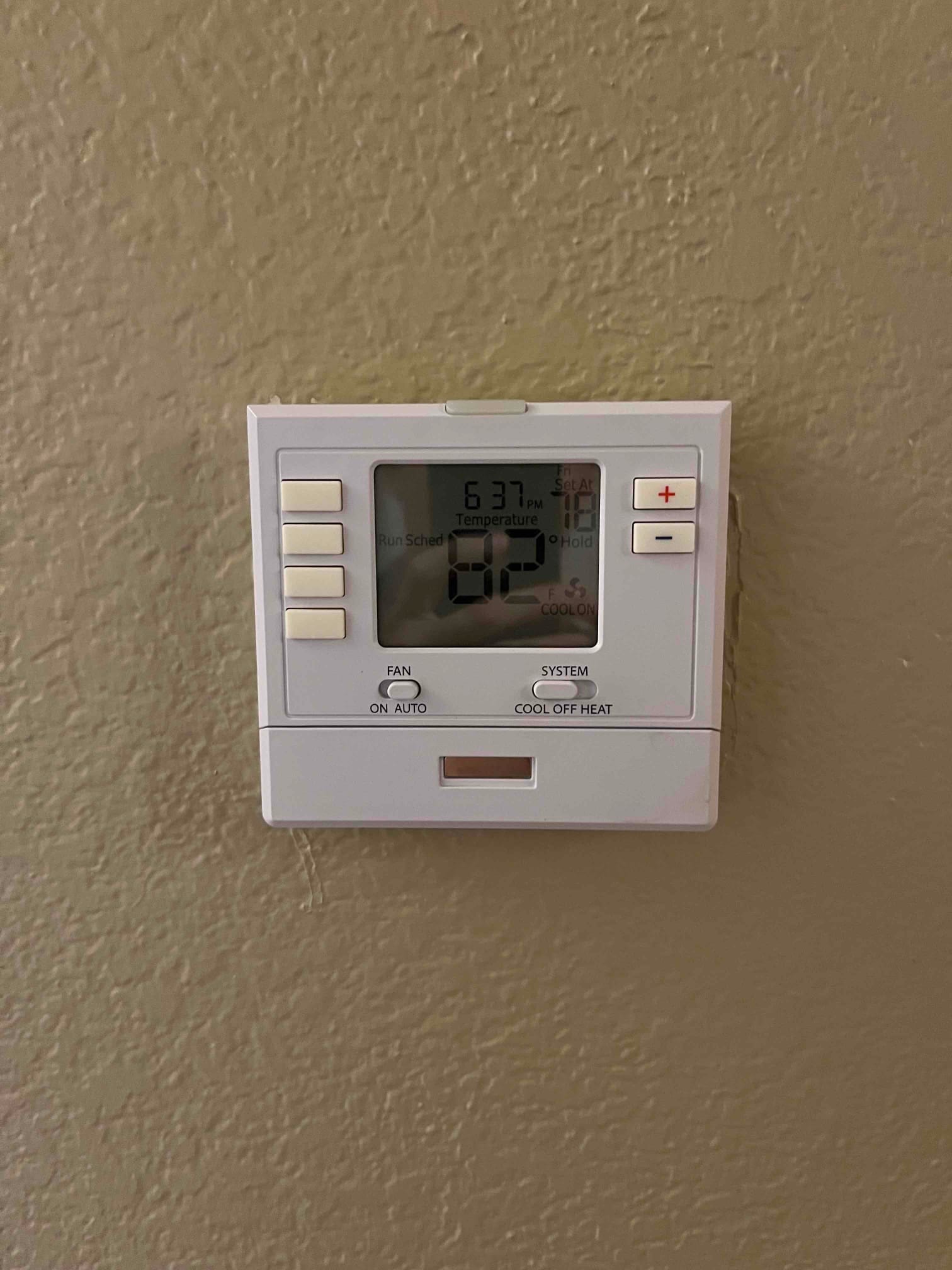 Wall-mounted digital thermostat shows 82°F with COOL ON indicated and the fan switch set to AUTO.