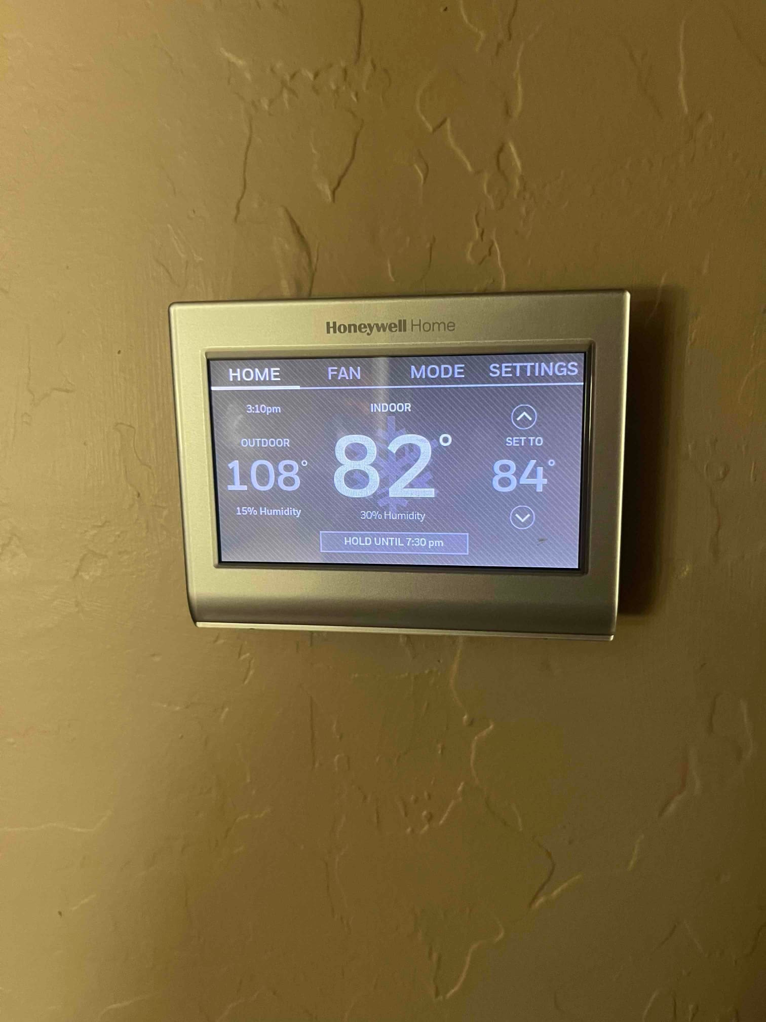 Wall-mounted touchscreen thermostat shows indoor 82°, outdoor 108°, setpoint 84°, with humidity readings displayed.