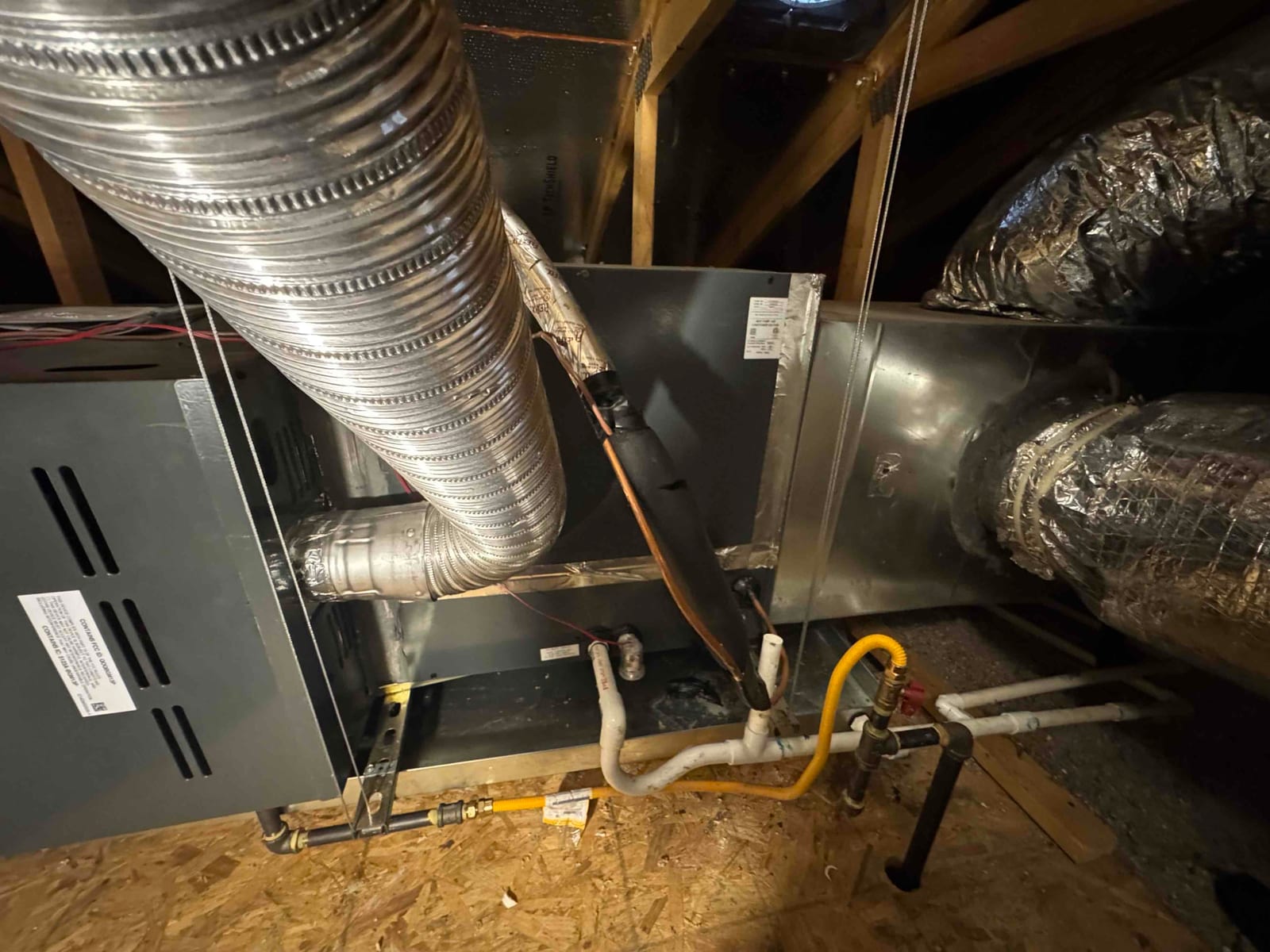 Attic air handler and furnace with metal ductwork, insulated refrigerant line, gas flex connector, and PVC condensate drain.