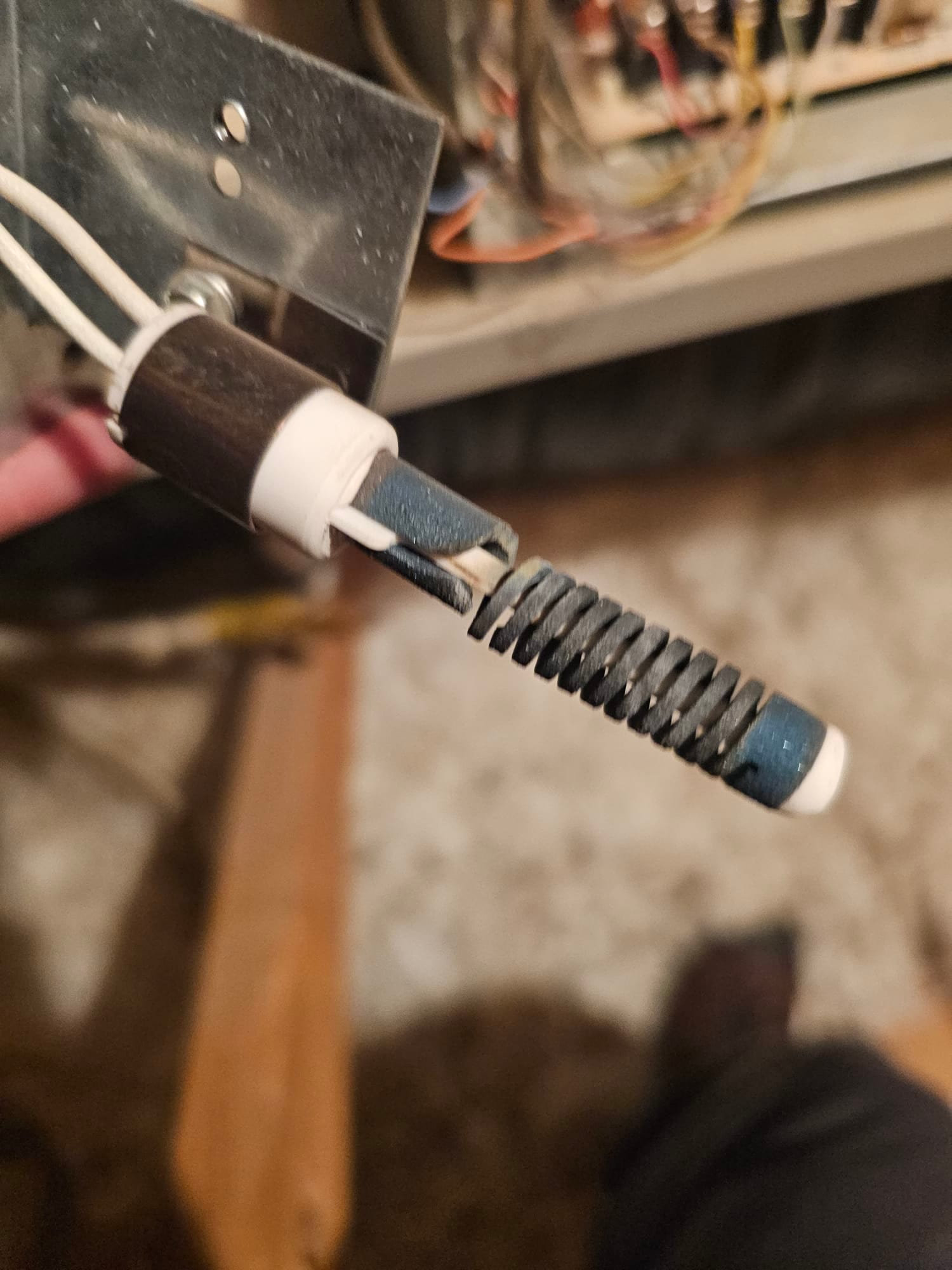 Ceramic holder with coiled metal probe and two white wires inside the HVAC unit cabinet near control wiring.