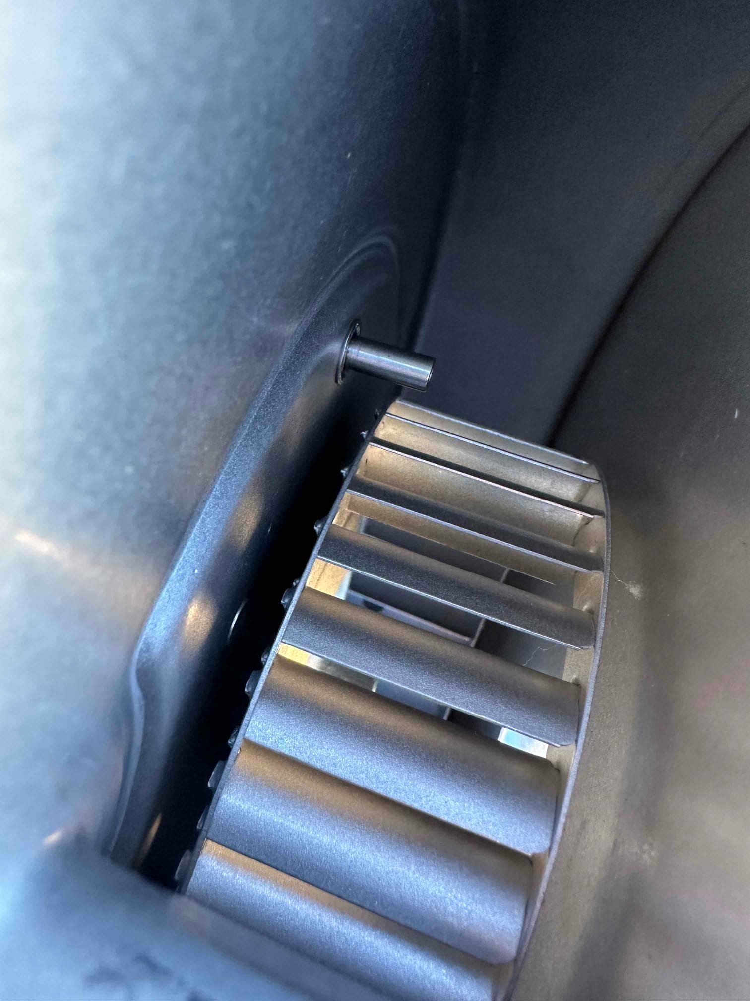 Close-up of a clean metal blower wheel inside the HVAC blower housing, showing fins and hub set screw.