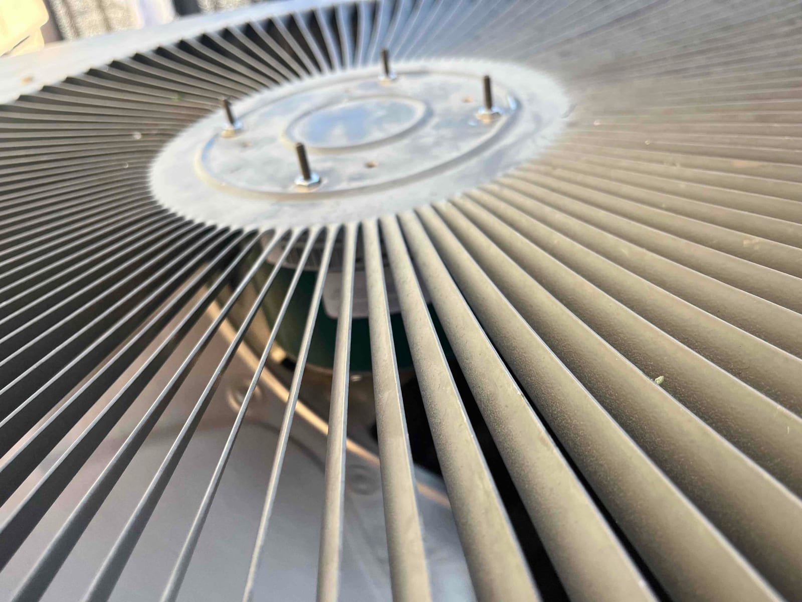 Close-up of outdoor condenser fan guard and center hub with mounting studs visible across the grille.
