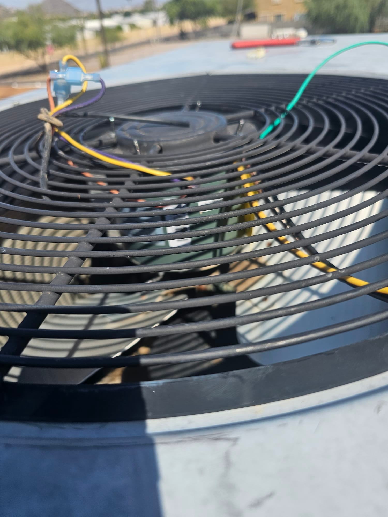 Condenser fan grille with exposed wiring and wire-nut connections on rooftop outdoor unit.