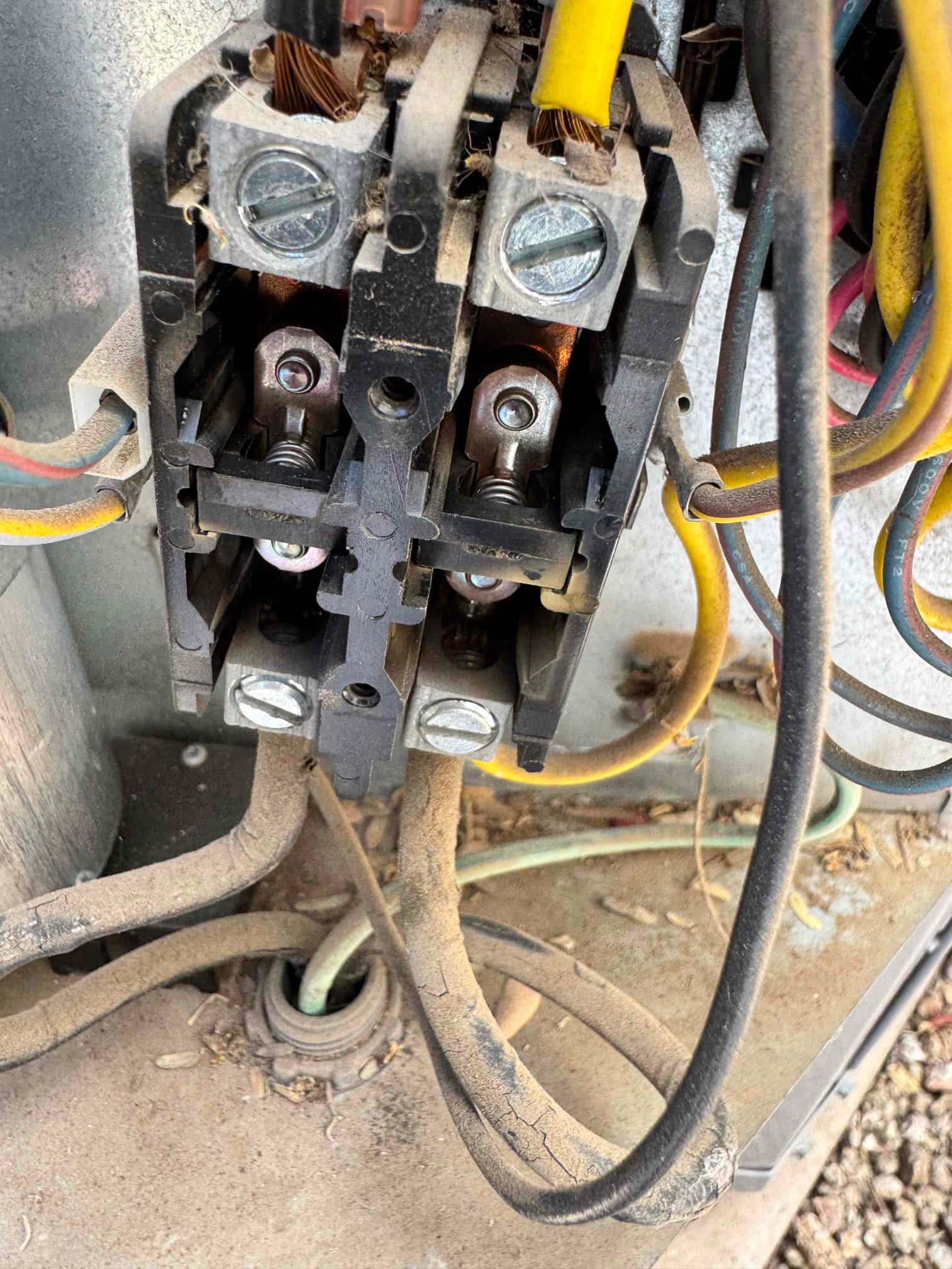 Contactor with wiring and screw terminals, showing dust buildup and frayed wire strands at connectors.