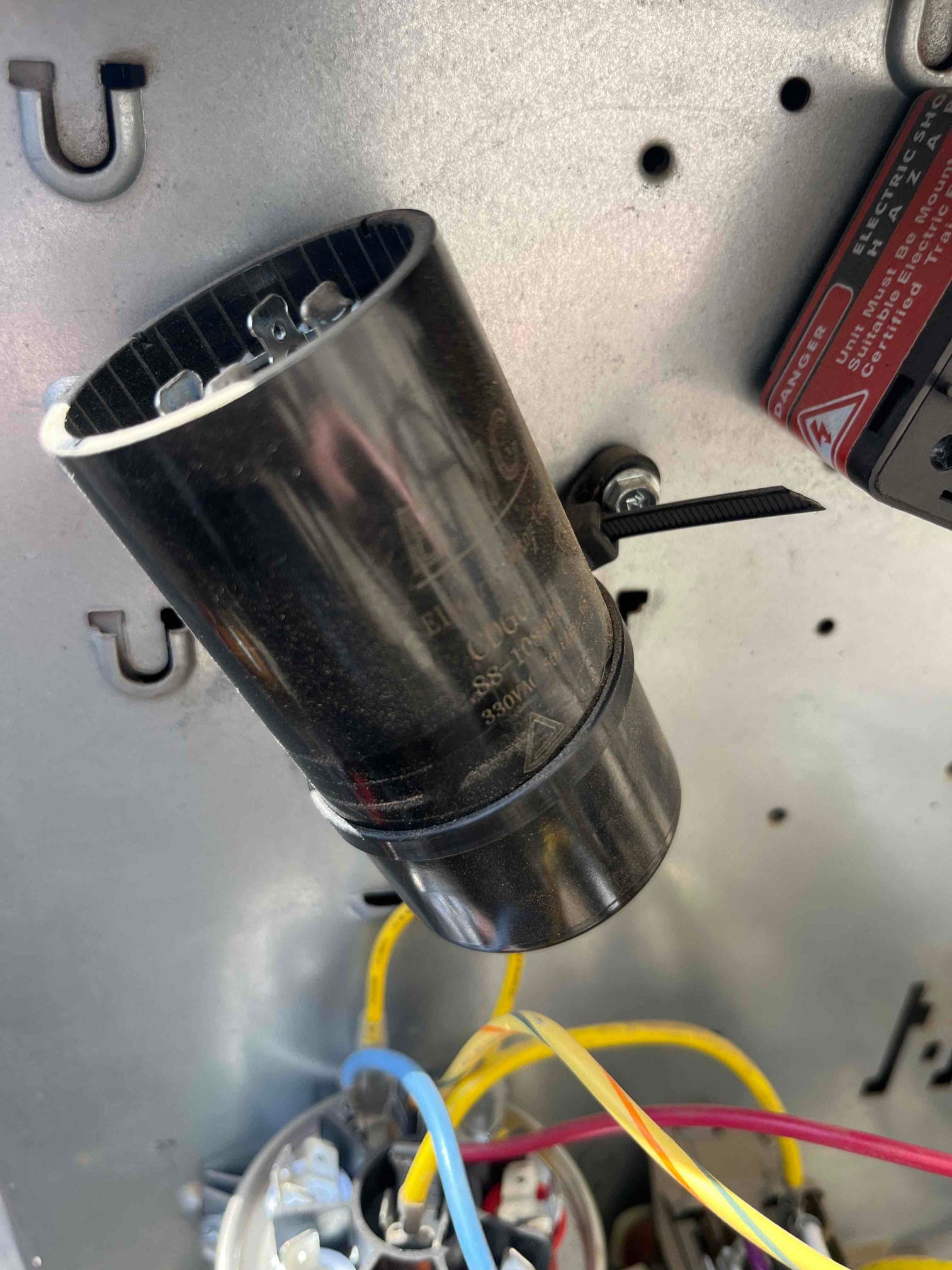 Cylindrical capacitor mounted inside the control compartment, with yellow, blue, and red wires routed to nearby components.