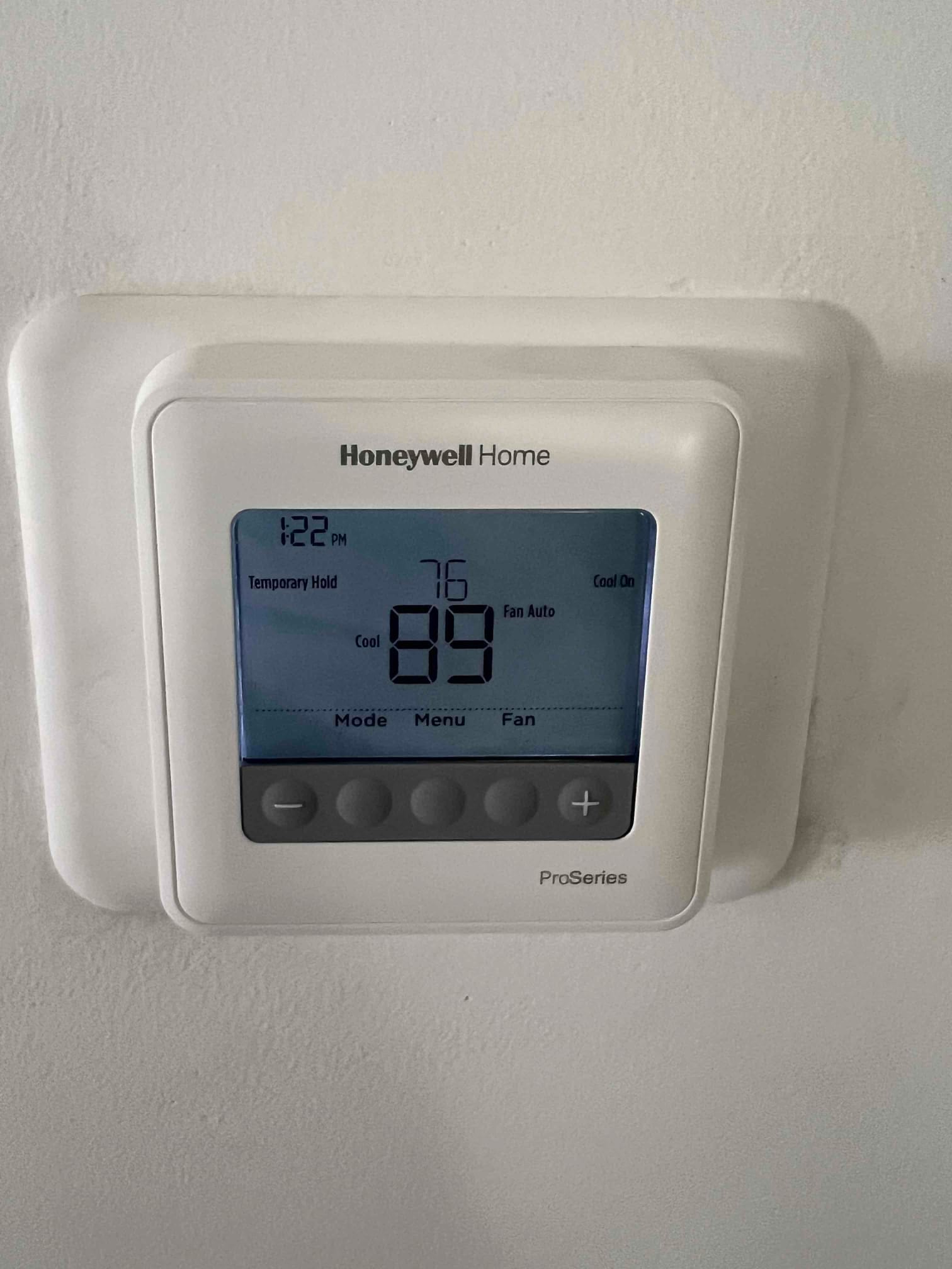 Digital thermostat on wall displaying 76°F room temperature, cooling mode on, fan auto, setpoint 69°F.