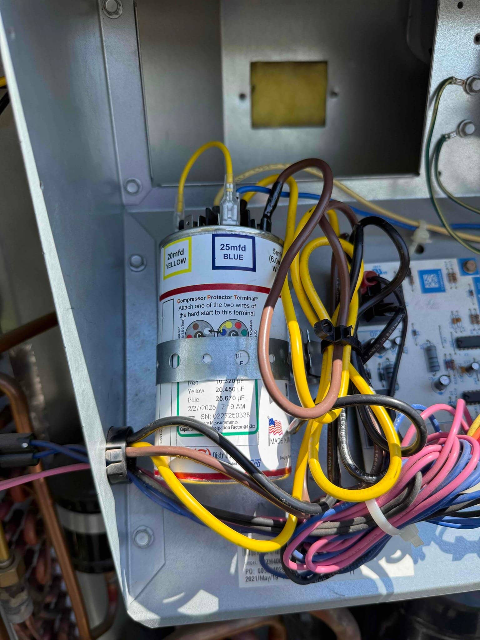 Dual capacitor labeled 25 mfd BLUE and 20 mfd YELLOW with multiple wires connected inside the control compartment.