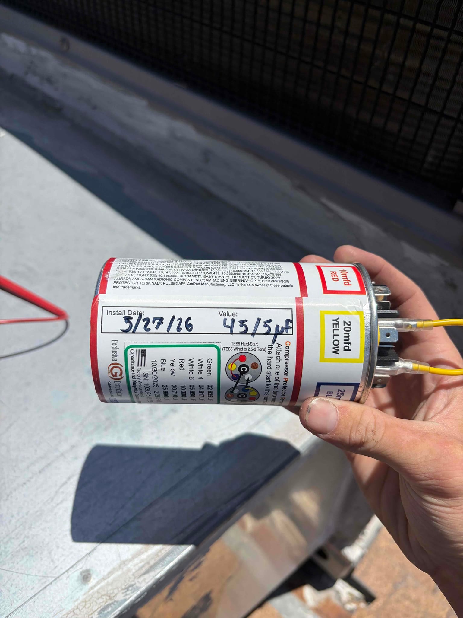 Dual-run capacitor labeled 45/5 μF with wiring terminals visible and yellow wires connected to the top.