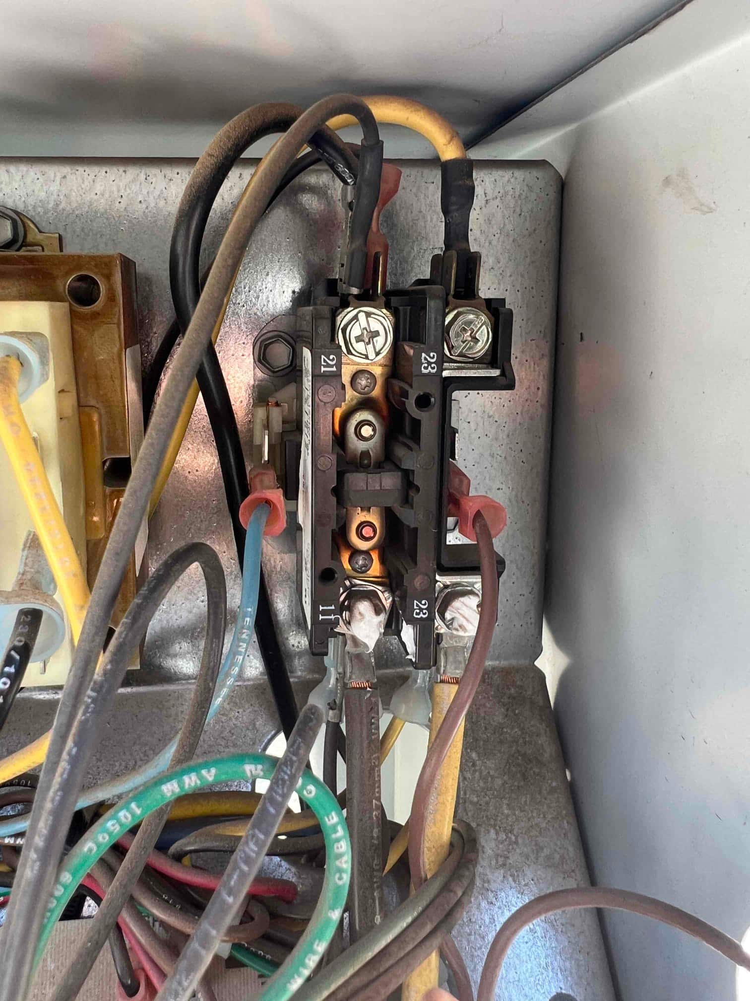Electrical contactor inside outdoor unit control compartment, with multiple wires connected and terminals labeled 21, 23, and 11.