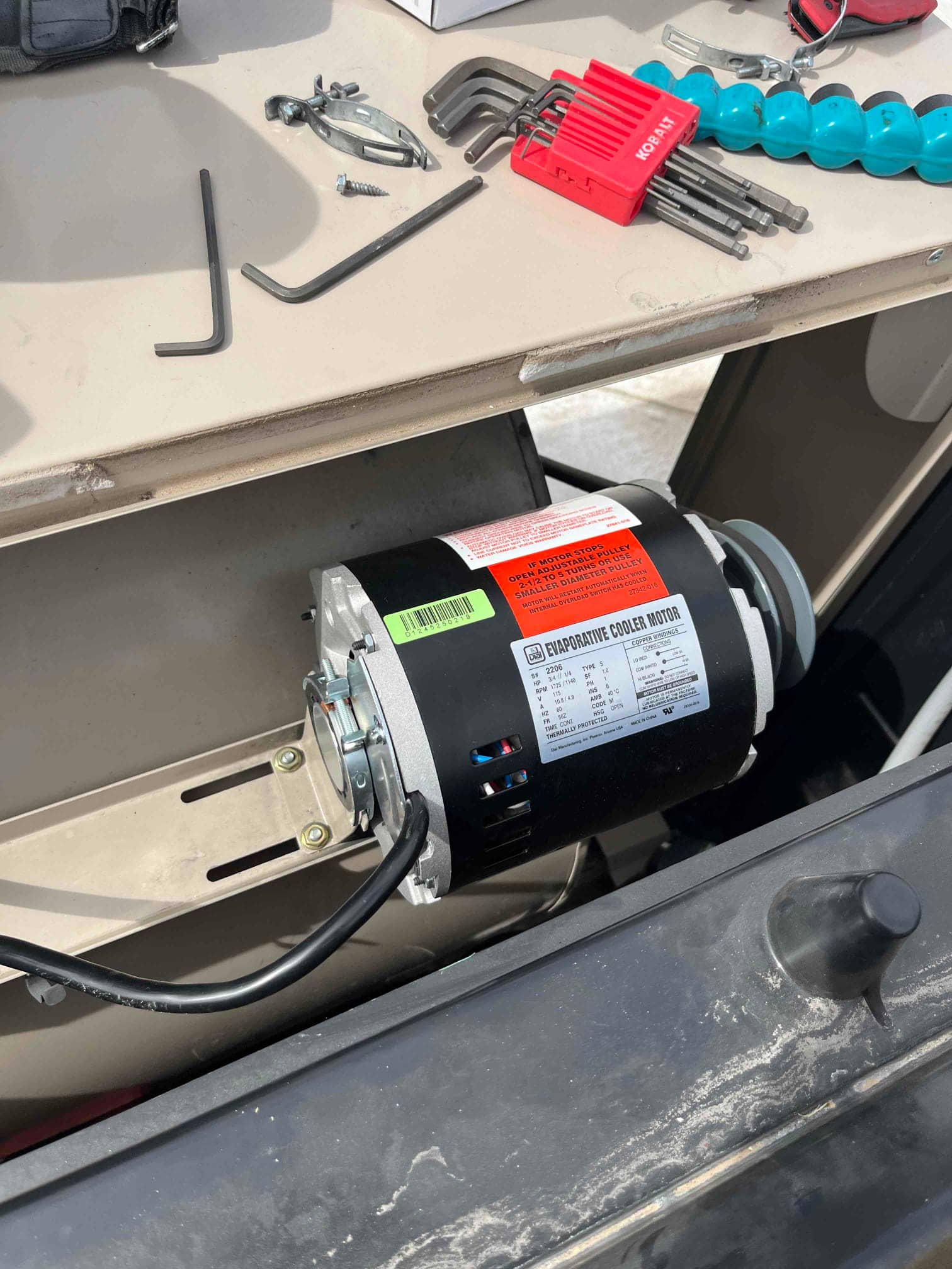 Evaporative cooler motor installed in the housing with power lead connected and specification label visible on the casing.