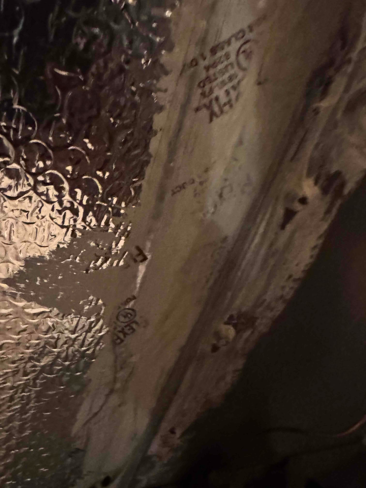 Foil-faced bubble insulation and mastic-sealed joint on ductwork, showing stamped UL markings.