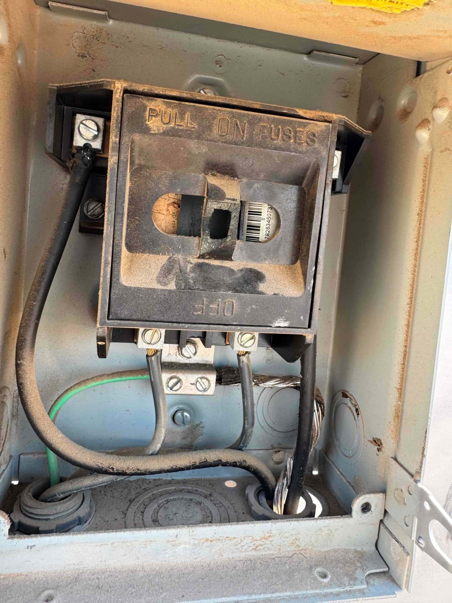 Fused pull-out disconnect in the service box showing connected line, load, and ground wires with visible dust.