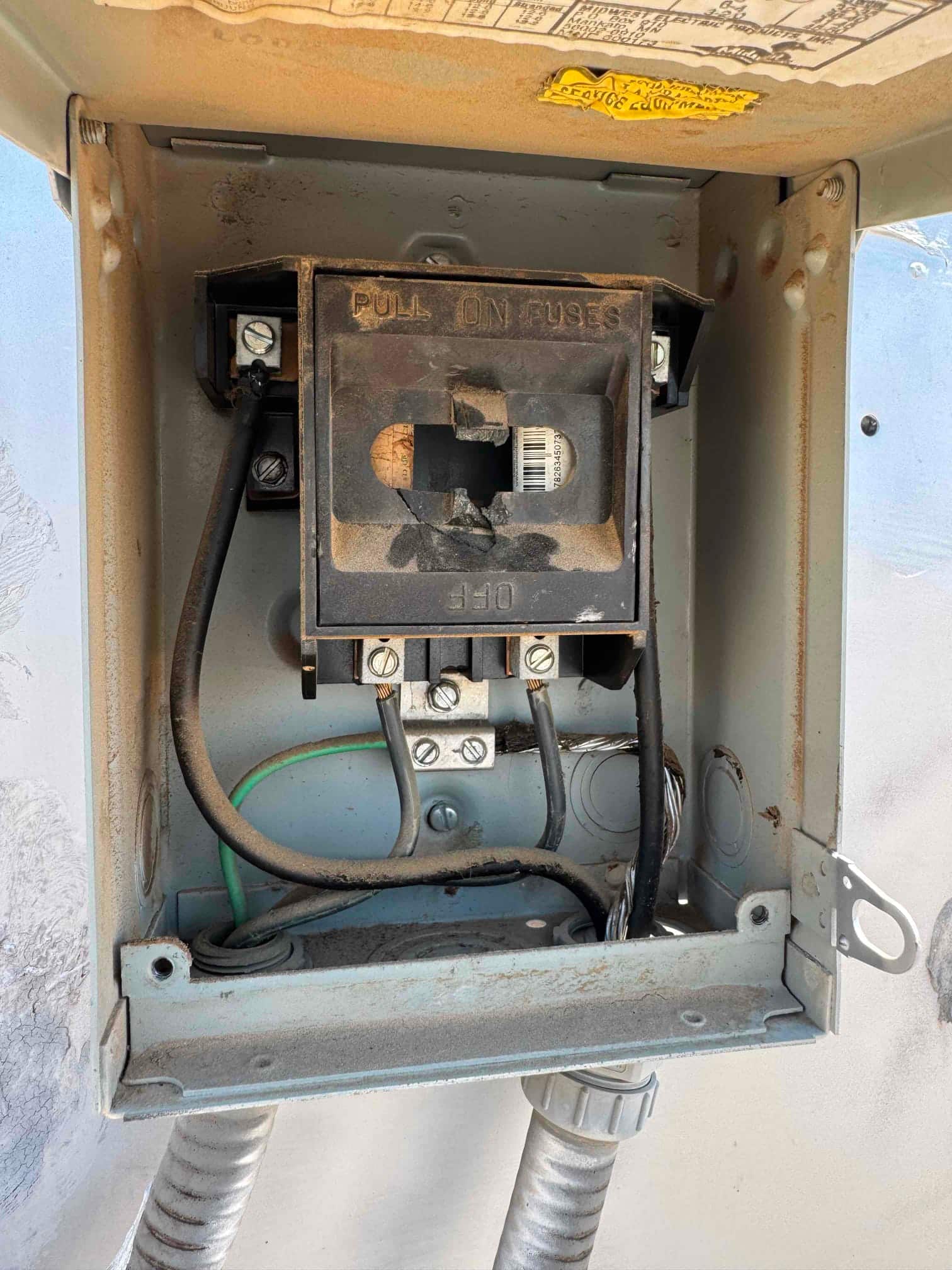Fused pull-out disconnect in the service box, cover open, showing line and load wiring and ground conductor.