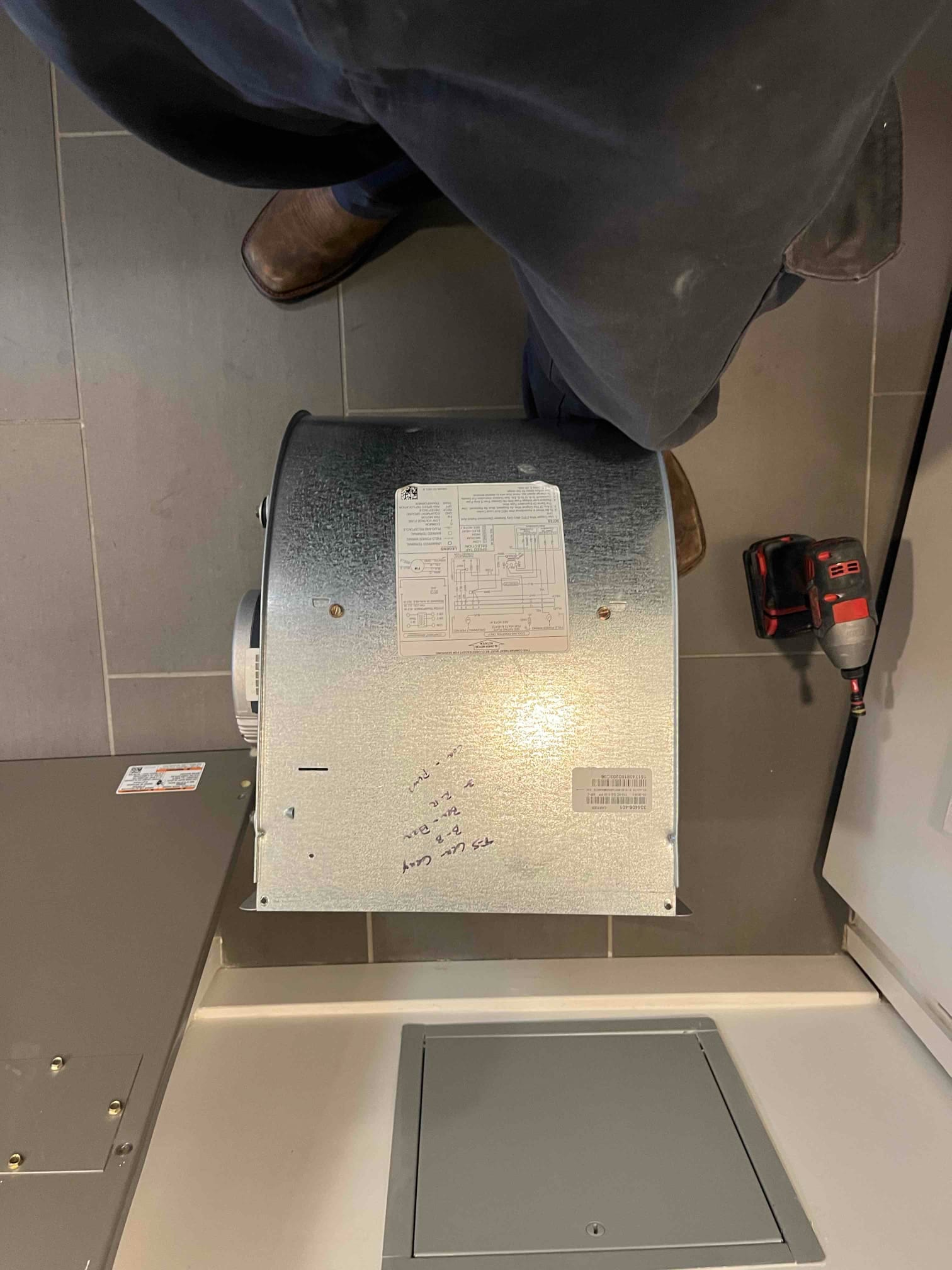 Galvanized blower assembly on a work surface with wiring diagram label and handwritten notes on the housing.