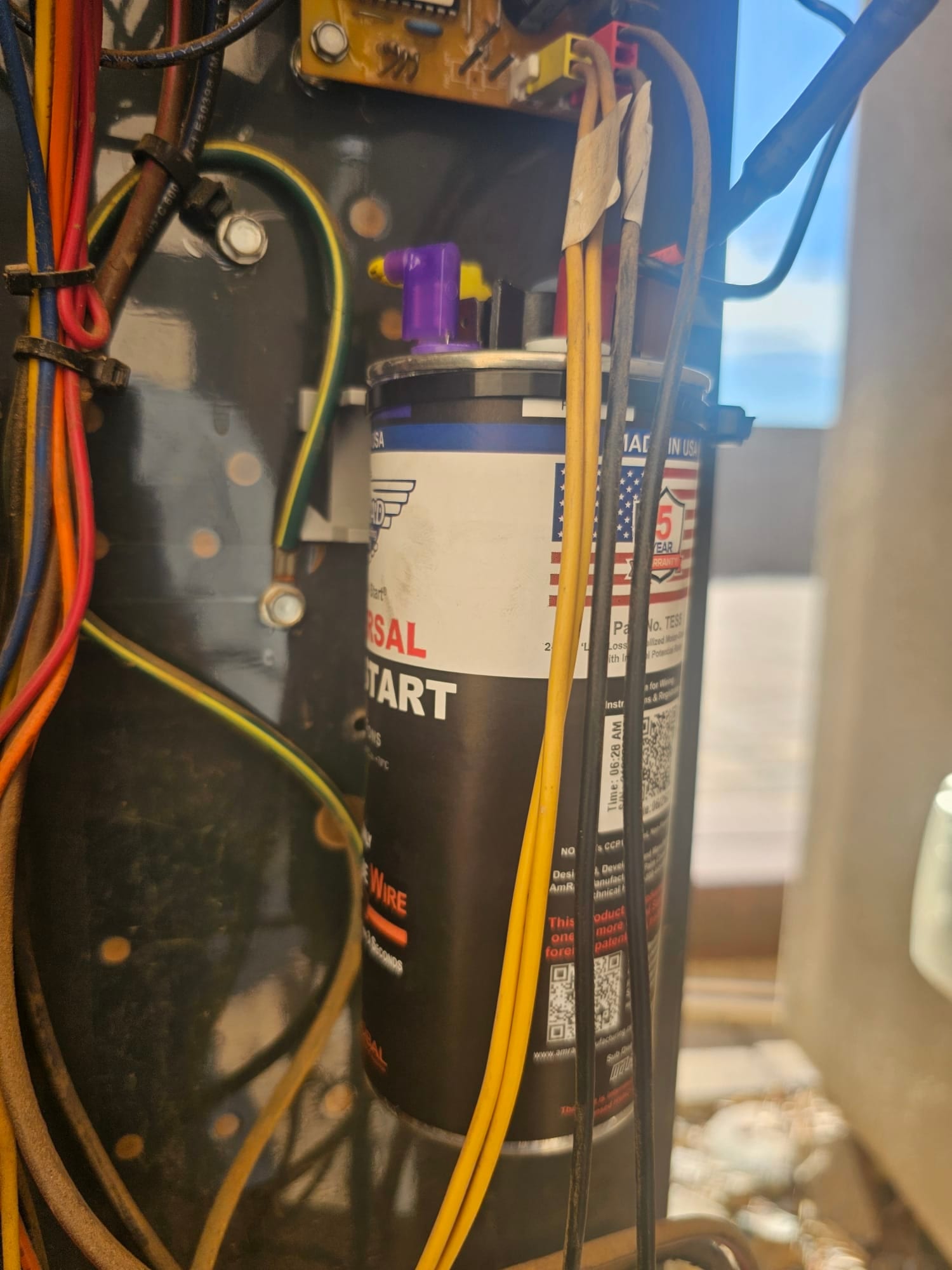 Hard-start capacitor kit canister with connected wiring inside the condenser control compartment.