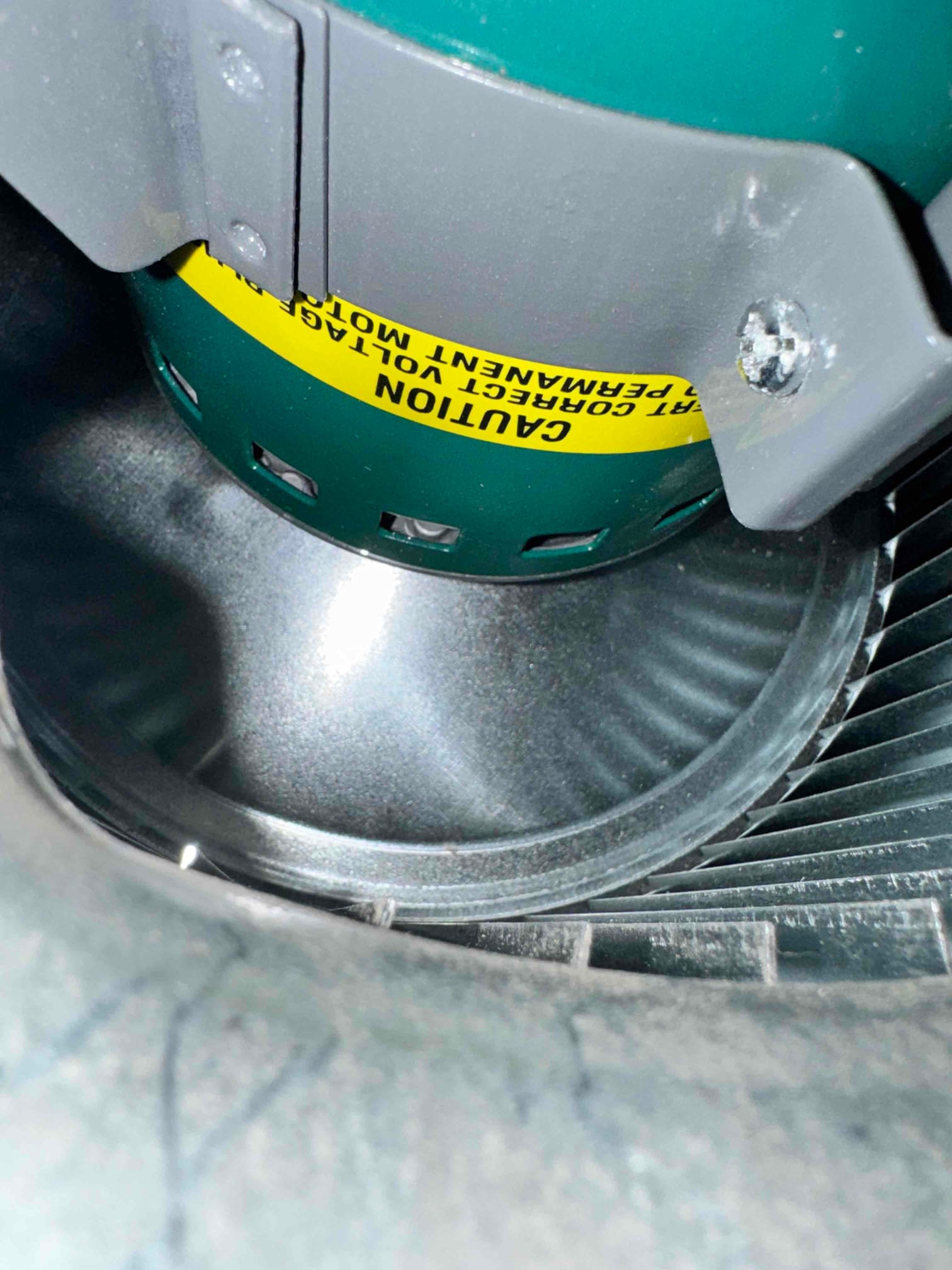 Indoor blower motor housing and squirrel-cage wheel inside the air handler, showing metal fins and mounting bracket.
