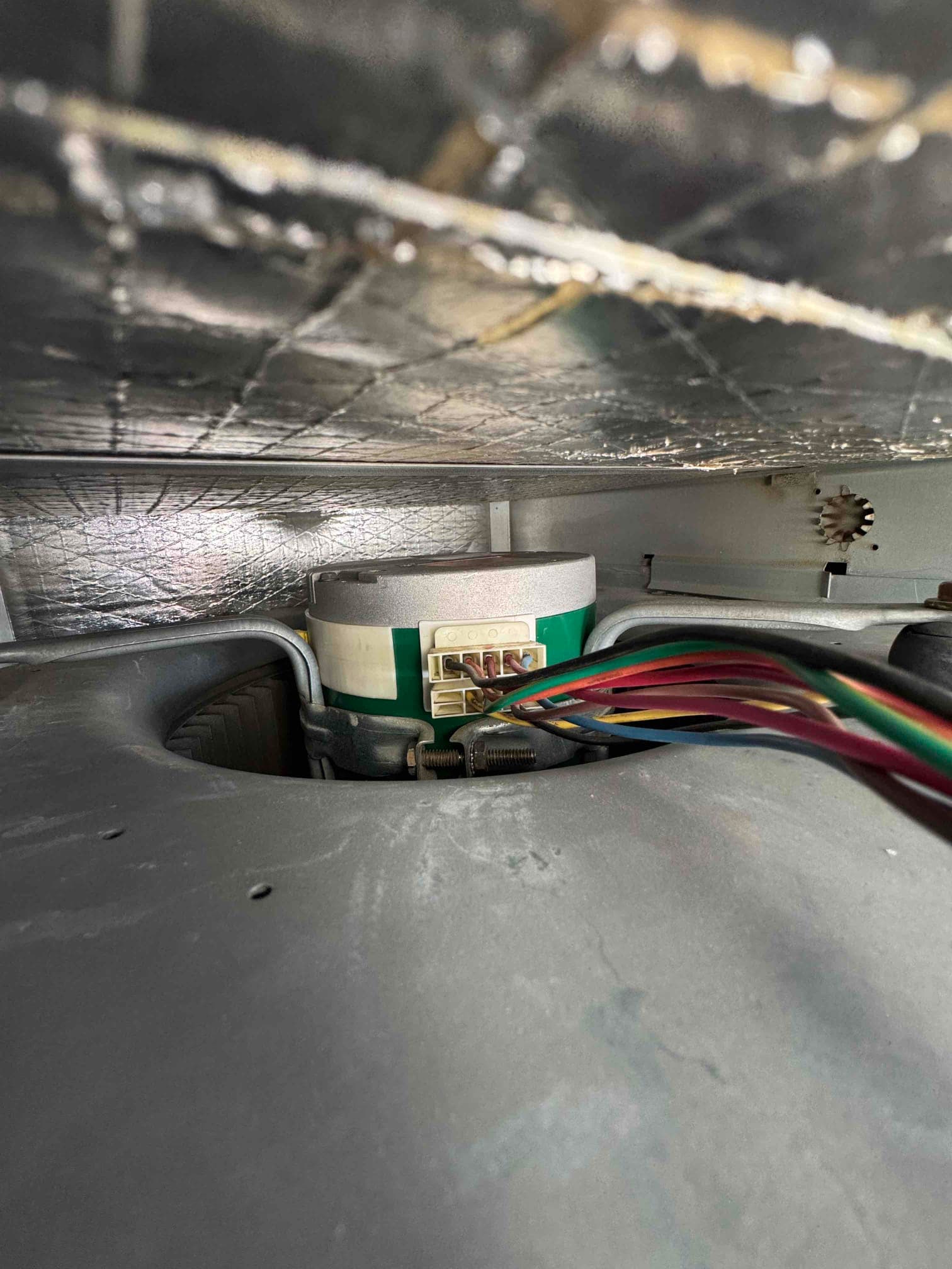 Indoor blower motor with multi-color wiring harness and connector attached, visible inside the air handler housing.