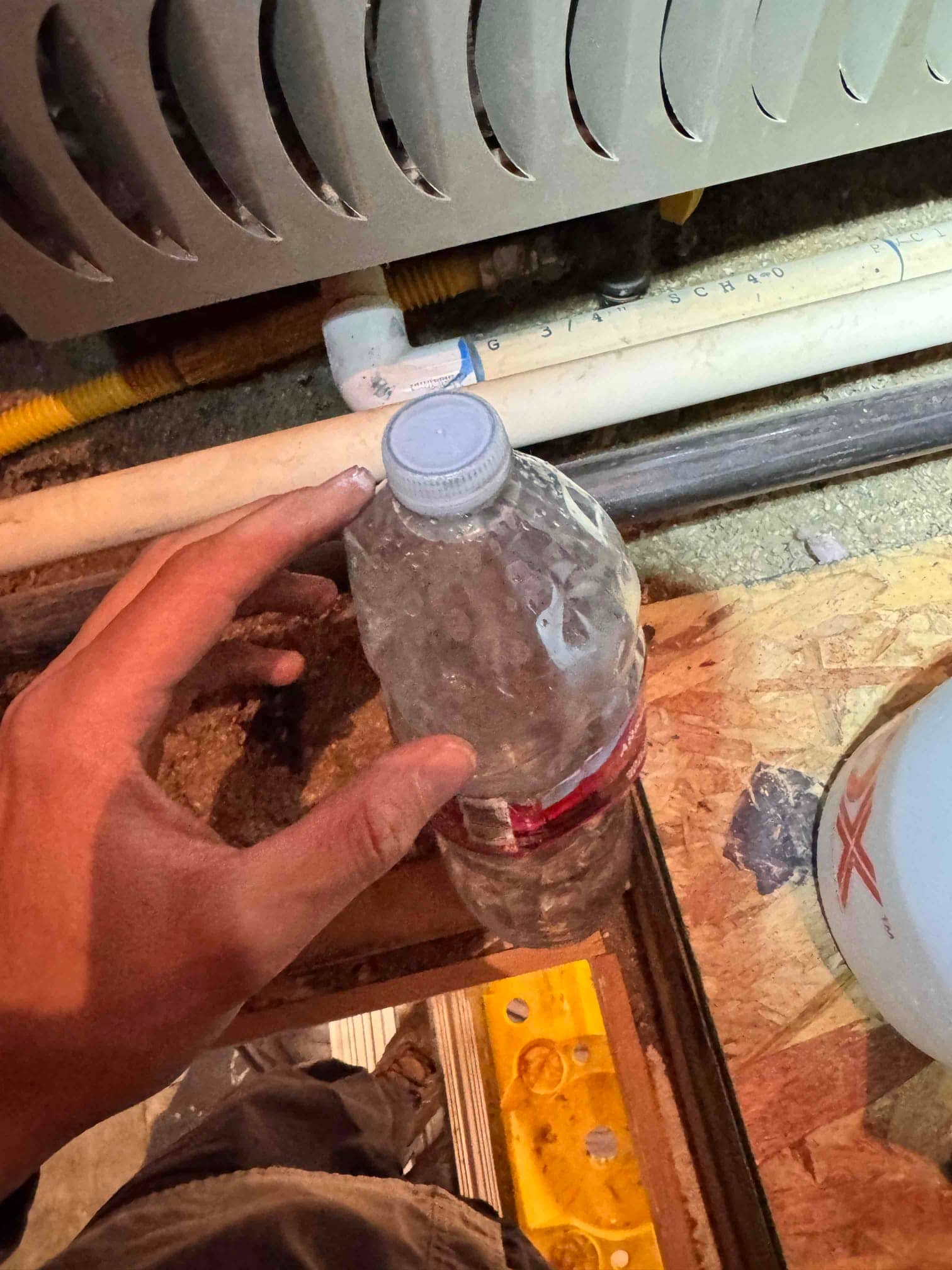 Metal HVAC cabinet base with 3/4 SCH 40 PVC drain piping and a yellow flexible gas connector routed beneath.