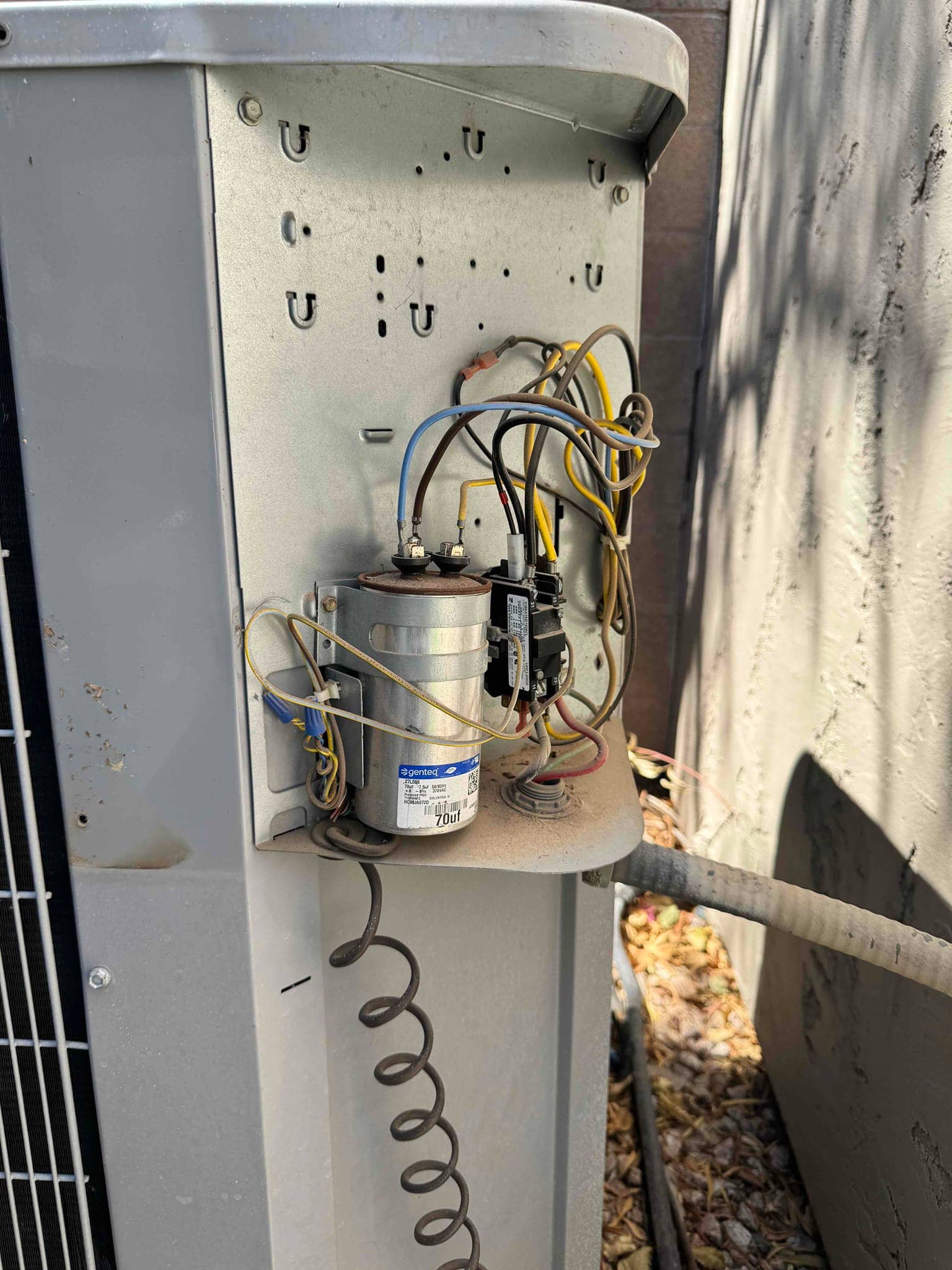 Outdoor condenser control compartment open, showing dual-run capacitor with wiring and a contactor mounted, with dust accumulation.